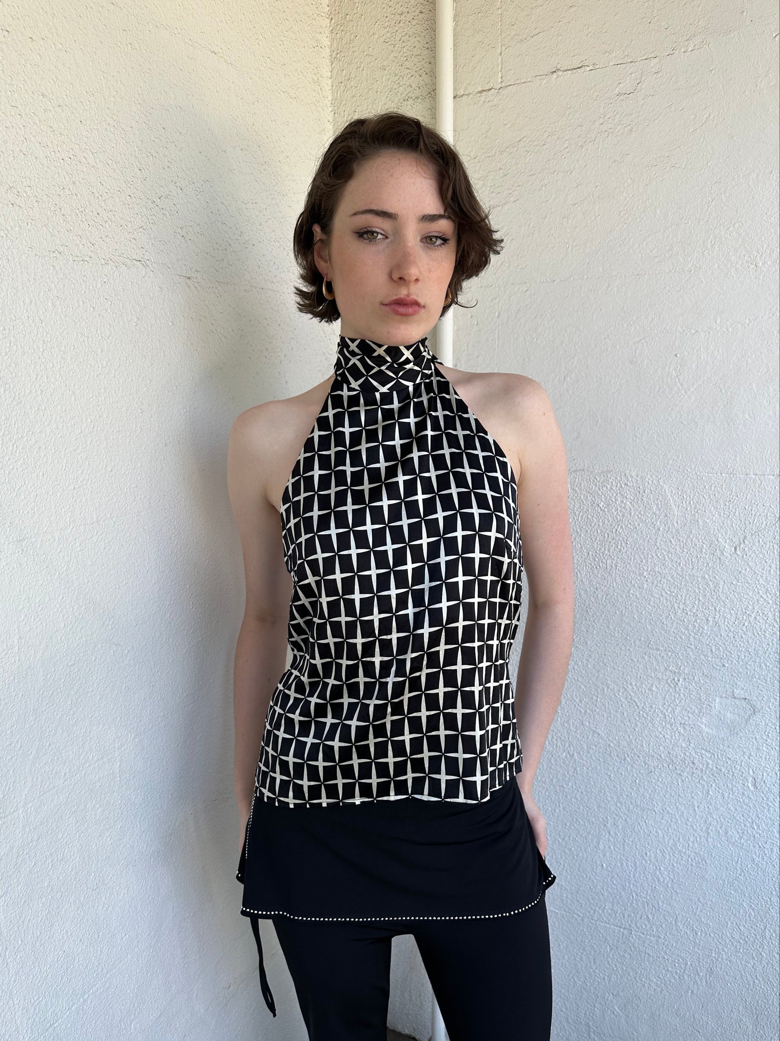 Woman Dressed in Y2K Black and white diamond pattern halter neck top featuring a striking geometric print with a flattering tie-back neckline.