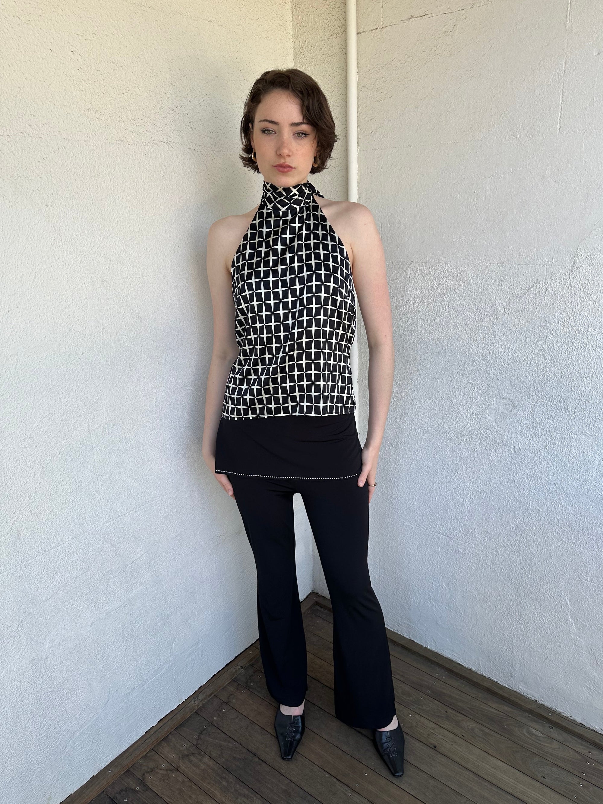 Woman Dressed in Y2K Black and white diamond pattern halter neck top featuring a striking geometric print with a flattering tie-back neckline.