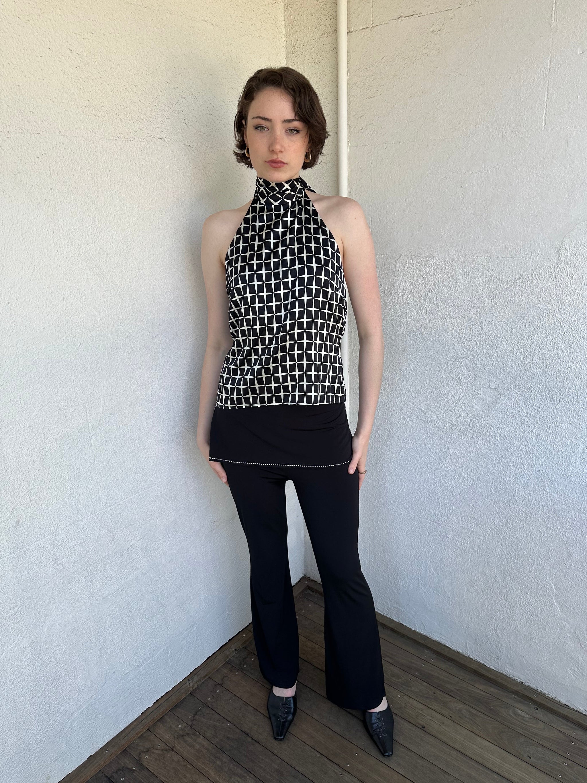 Woman Dressed in Y2K Black and white diamond pattern halter neck top featuring a striking geometric print with a flattering tie-back neckline.
