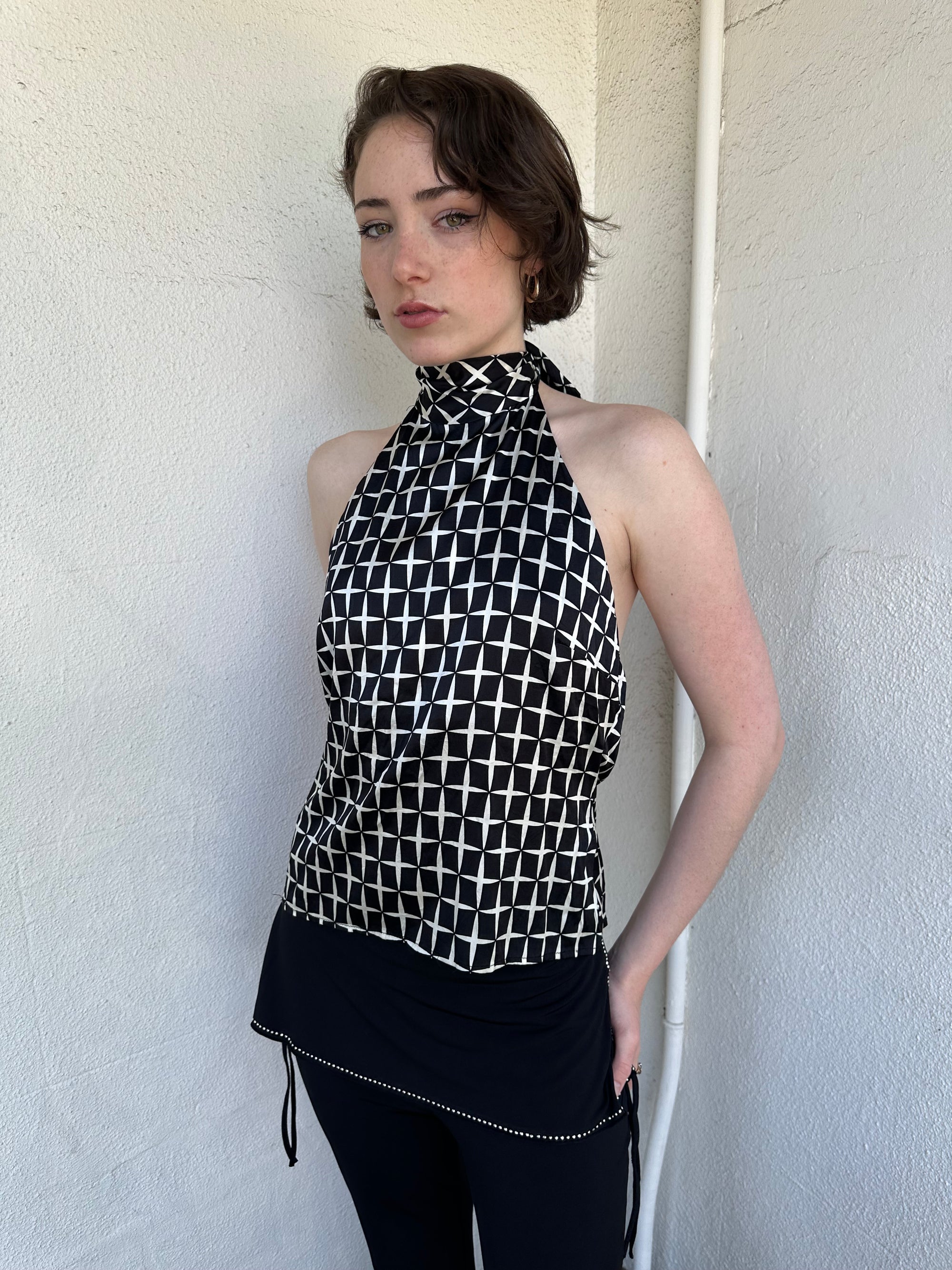Woman Dressed in Y2K Black and white diamond pattern halter neck top featuring a striking geometric print with a flattering tie-back neckline.