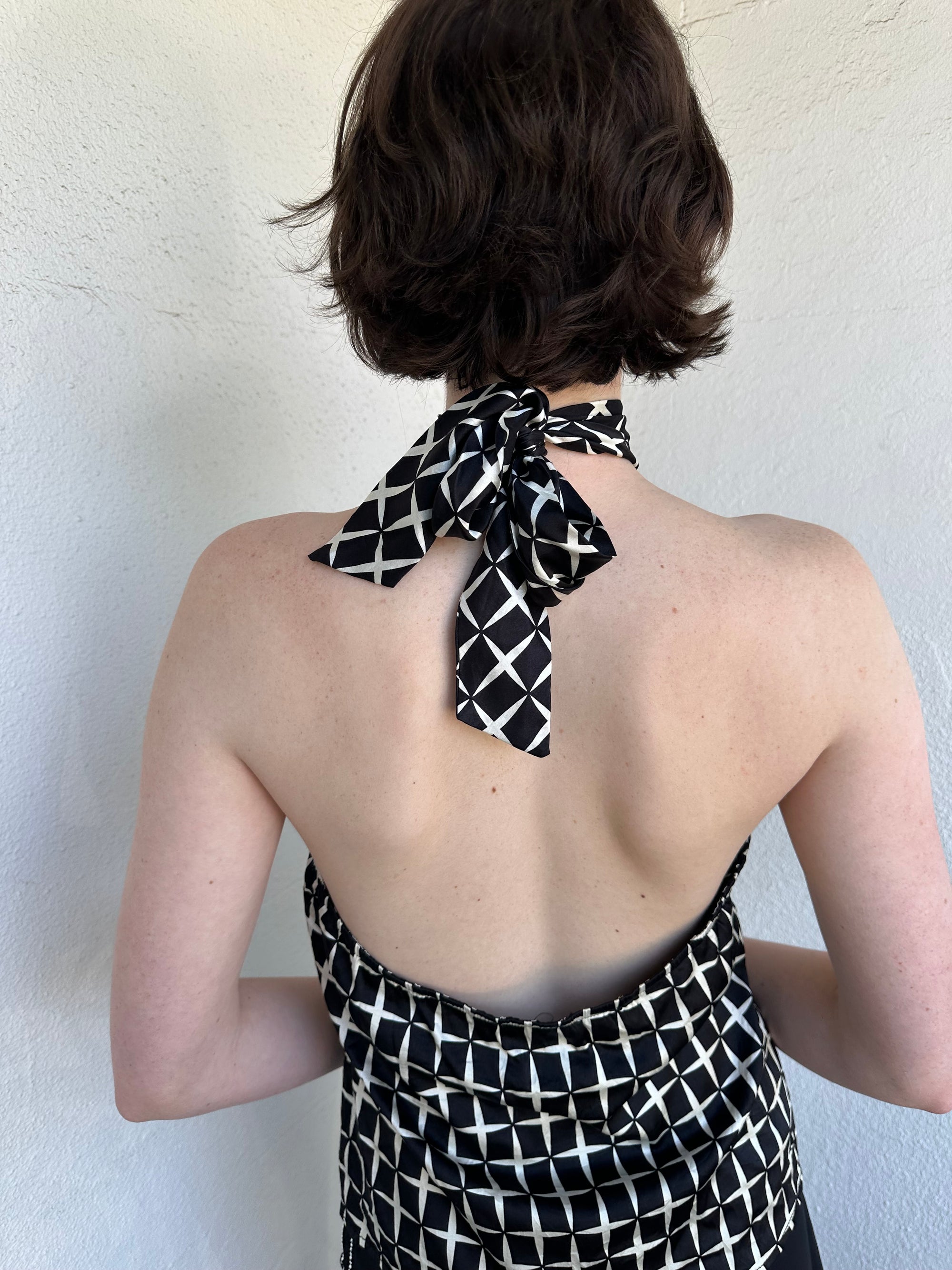 Woman Dressed in Y2K Black and white diamond pattern halter neck top featuring a striking geometric print with a flattering tie-back neckline.