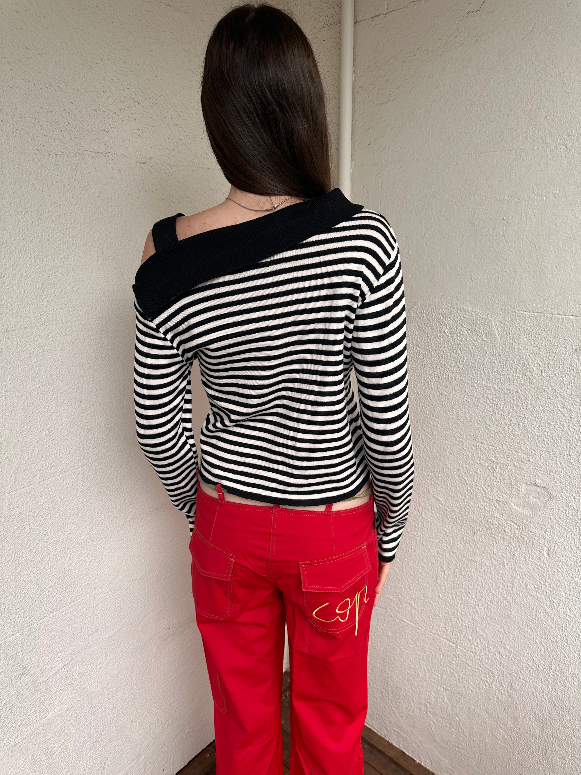 Women wearing a 00s Y2K lack and white stripe knitted top with an asymmetric collar and one-shoulder strap.