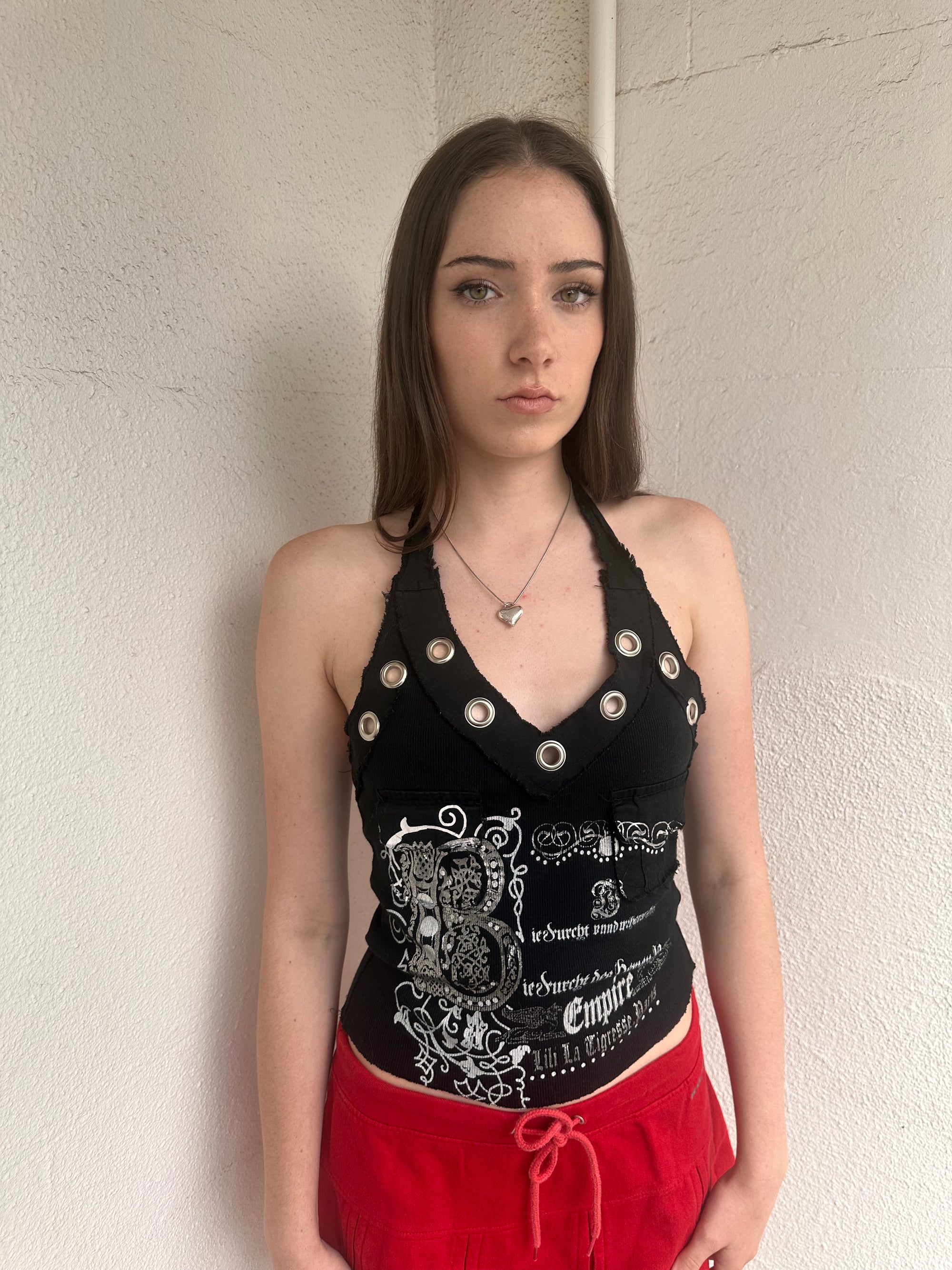 Woman wearing a Y2K 00s black grunge silver and white text graphic style halter top 
