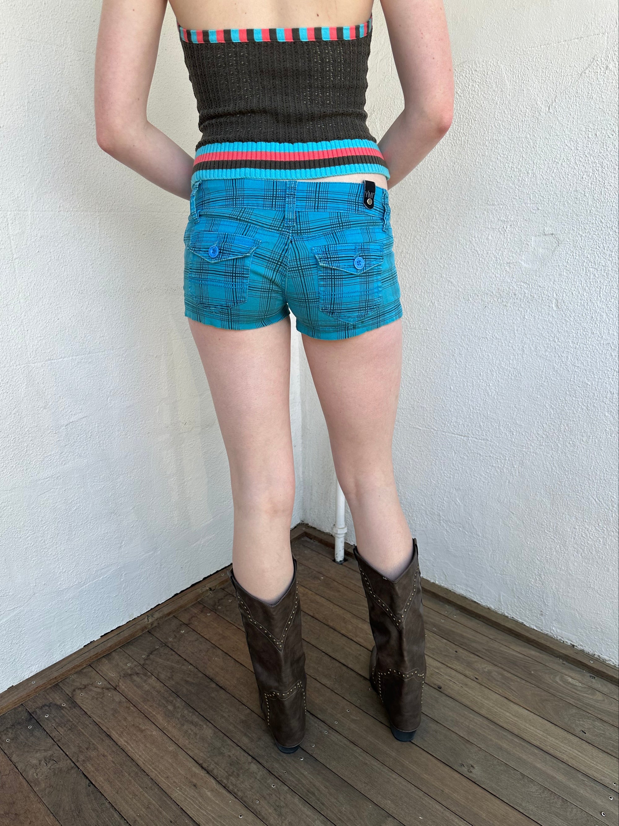 Woman Dressed in Y2K Blue and black plaid shorts featuring a bright blue base with black plaid detailing.