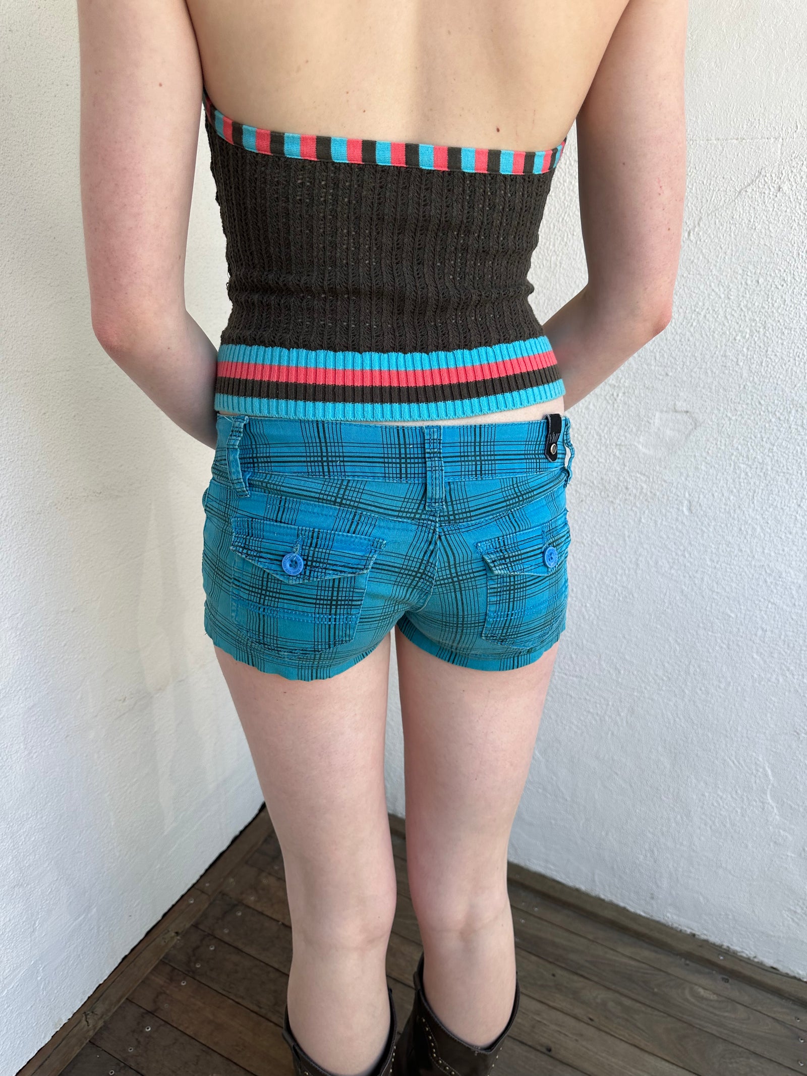 Woman Dressed in Y2K Blue and black plaid shorts featuring a bright blue base with black plaid detailing.