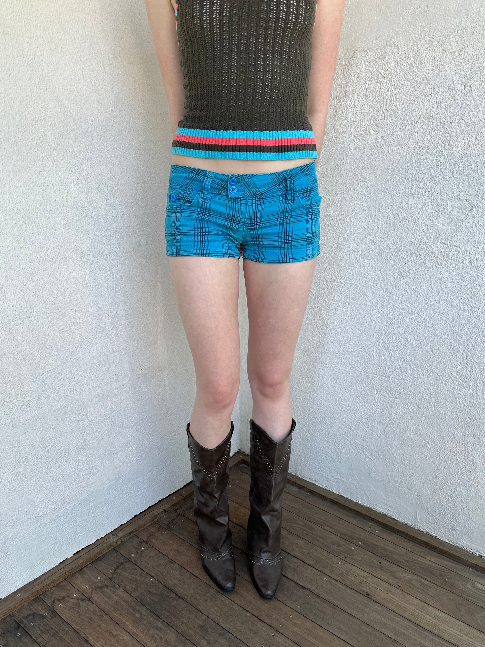 Woman Dressed in Y2K Blue and black plaid shorts featuring a bright blue base with black plaid detailing.