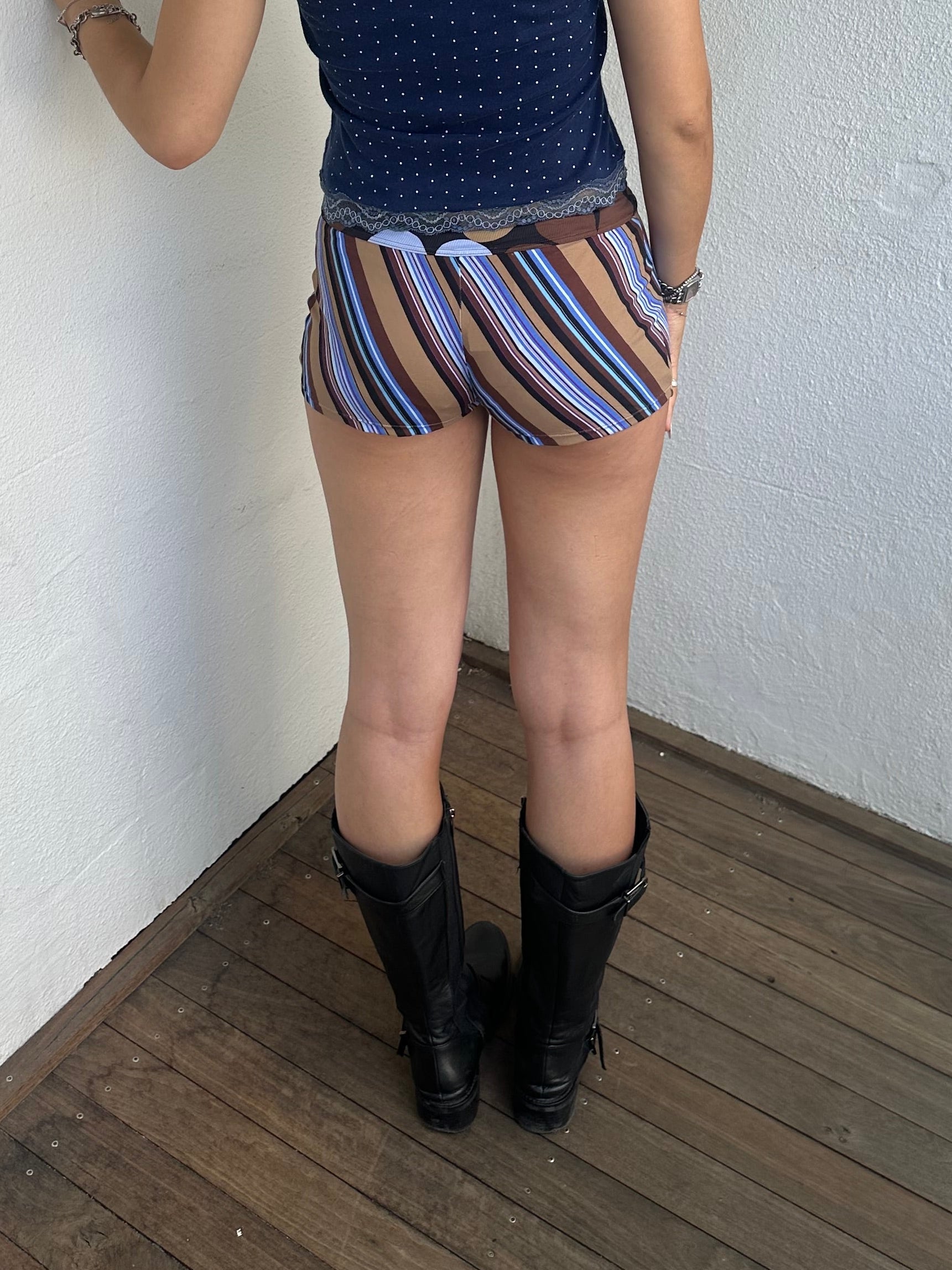 Woman Dressed in Y2K 00s Blue and brown stripe booty shorts featuring a multi-stripe pattern in brown, blue, and tan tones. 