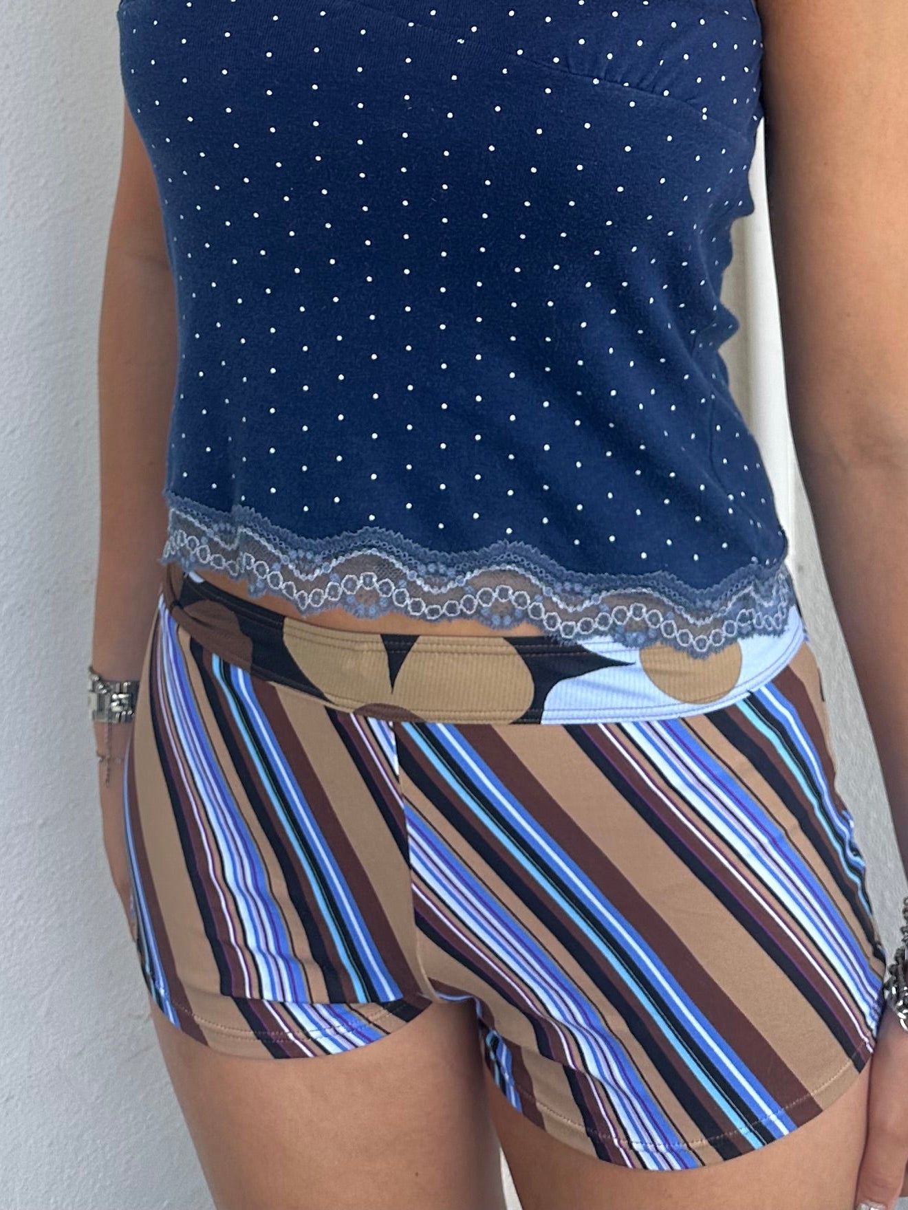 Woman Dressed in Y2K 00s Blue and brown stripe booty shorts featuring a multi-stripe pattern in brown, blue, and tan tones. 