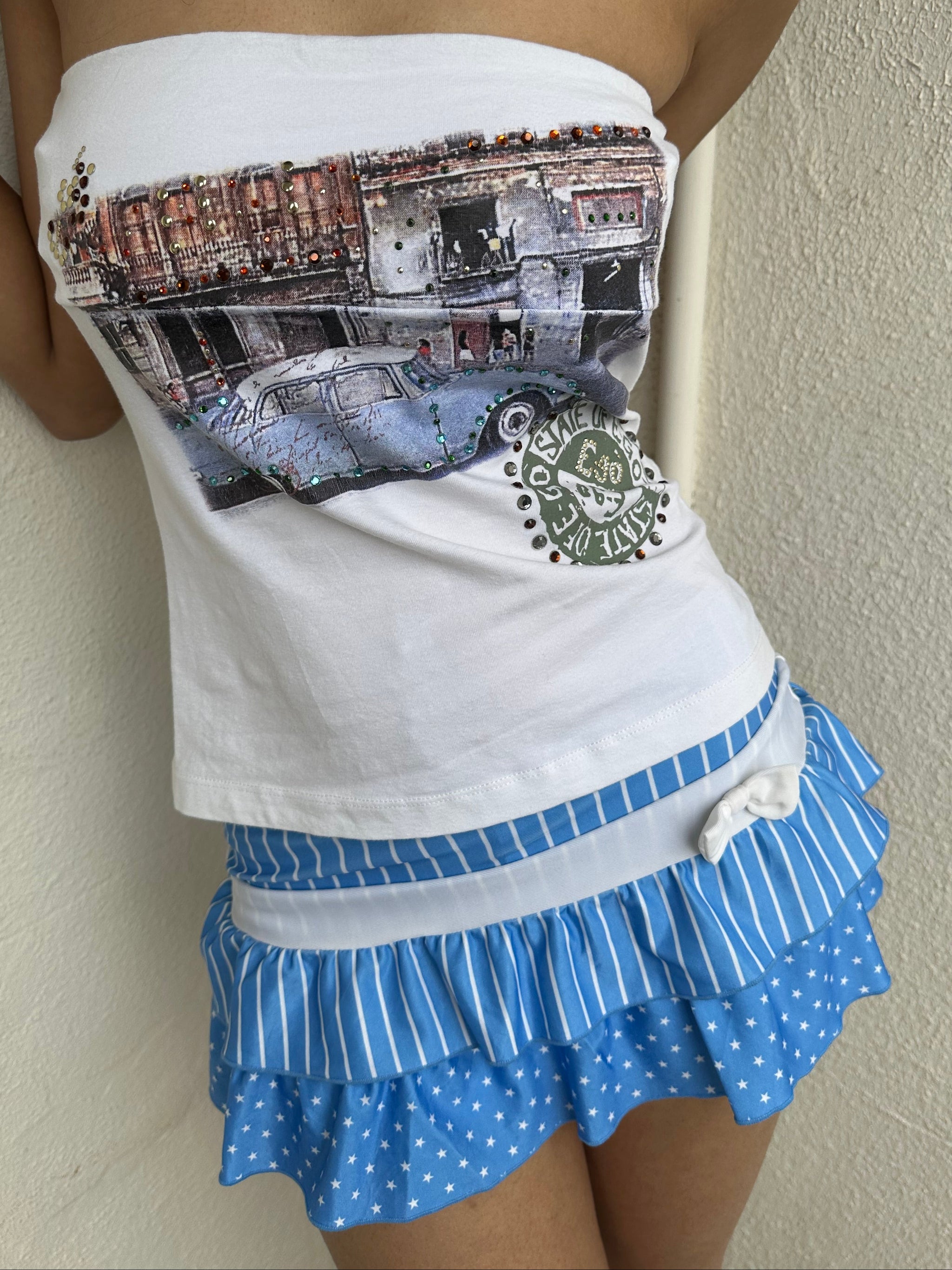 Woman Dressed in Y2K 00s Blue and white stars and stripes mini skort featuring layered ruffles with alternating pattern panels.