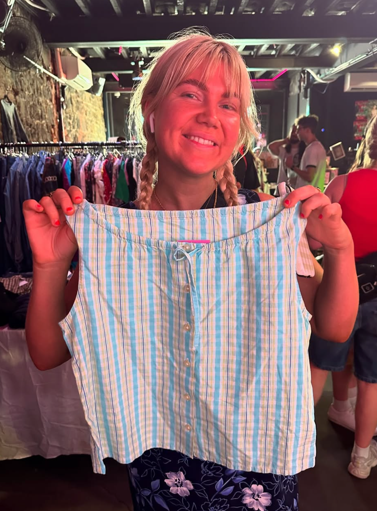 Woman holding up a blue and white striped shirt in a store setting