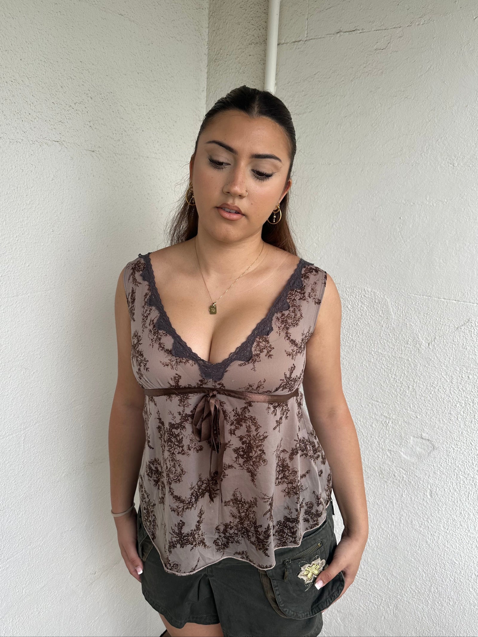 Woman Dressed in Y2K 00s Brown floral floaty tank top featuring a soft floral print with lace trim along the V neckline. 