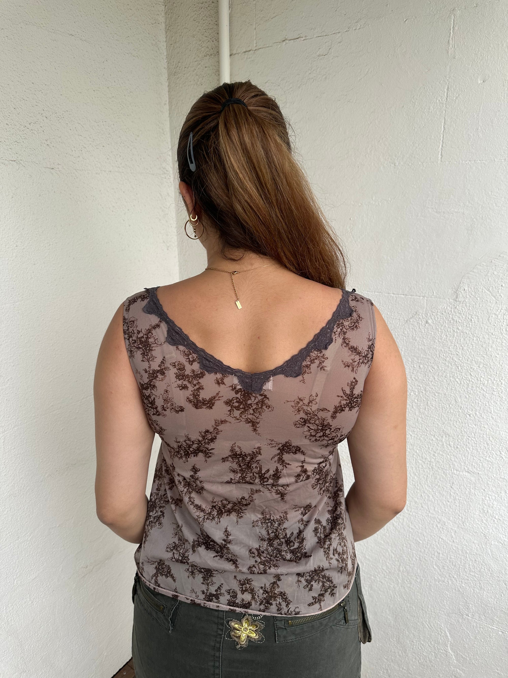 Woman Dressed in Y2K 00s Brown floral floaty tank top featuring a soft floral print with lace trim along the V neckline. 