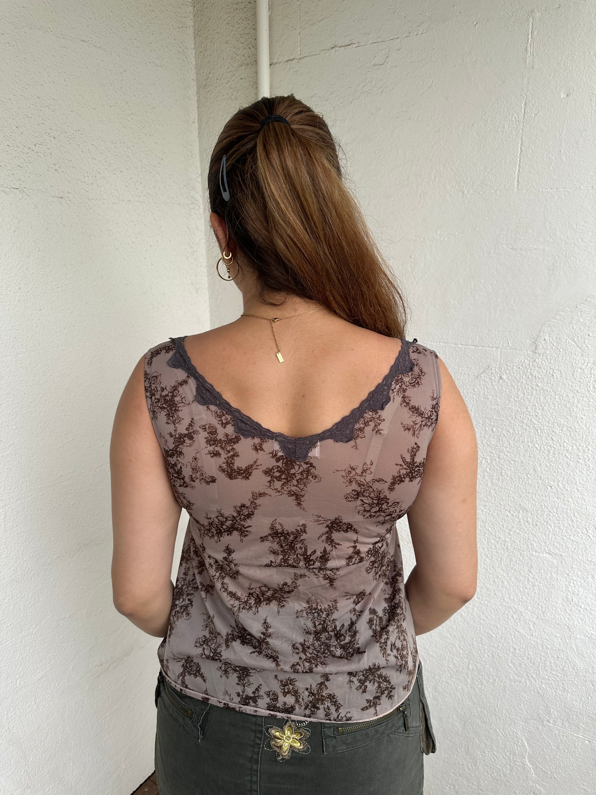 Woman Dressed in Y2K 00s Brown floral floaty tank top featuring a soft floral print with lace trim along the V neckline. 