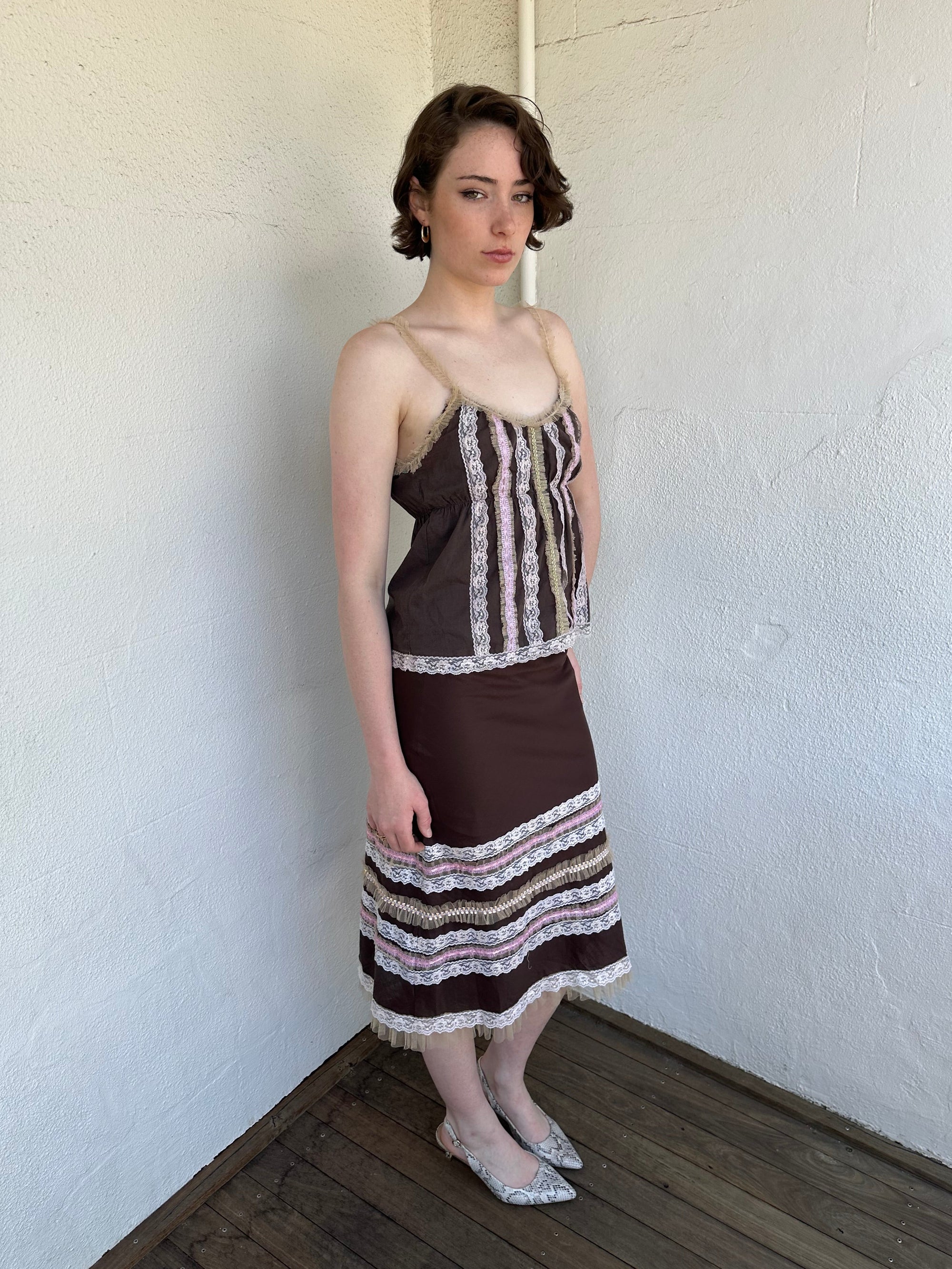 Woman Dressed in Y2K Brown and pink lace trim two piece set featuring a cami top and matching skirt detailed with cream lace and tulle trim throughout.