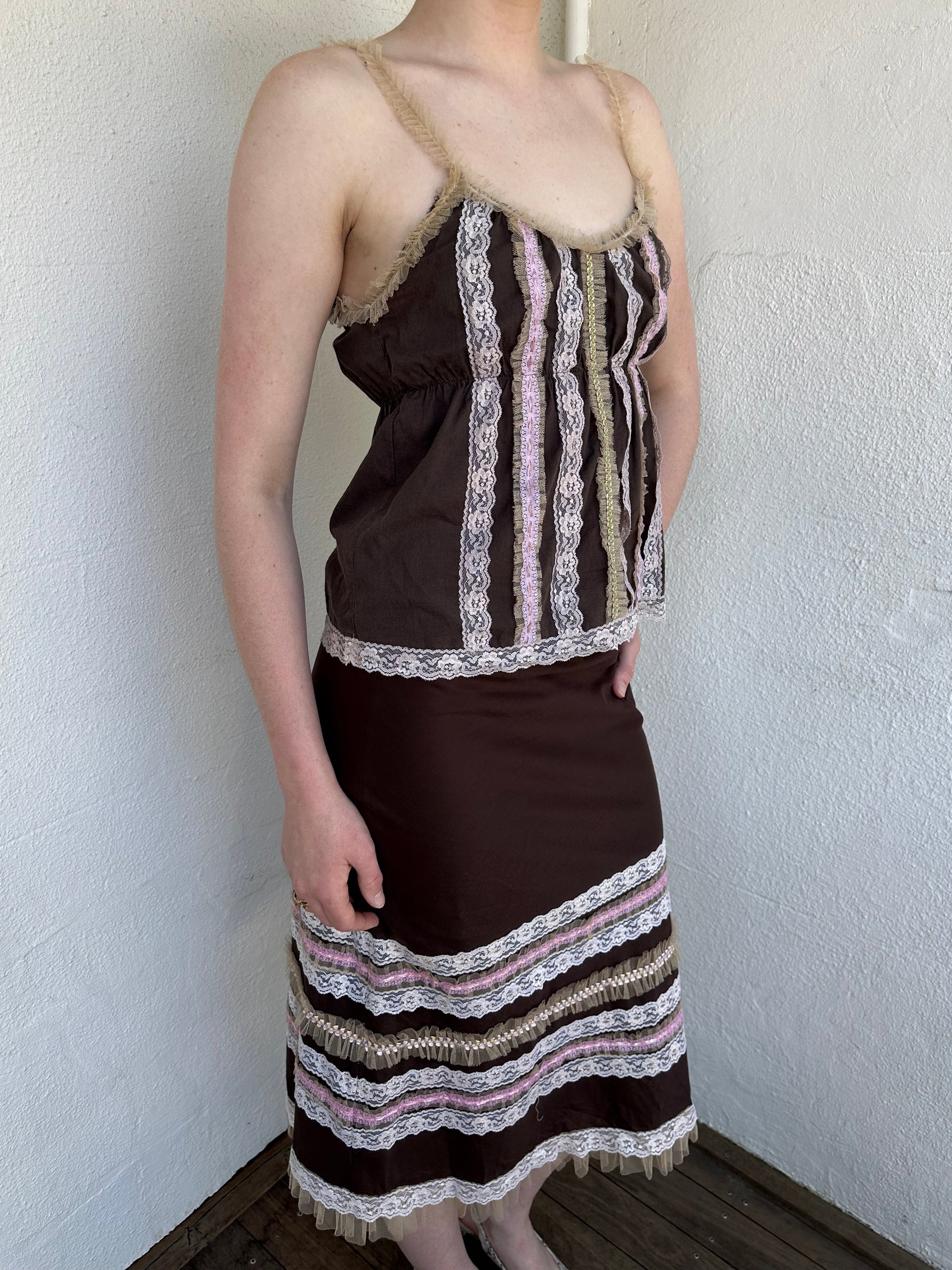Woman Dressed in Y2K Brown and pink lace trim two piece set featuring a cami top and matching skirt detailed with cream lace and tulle trim throughout.