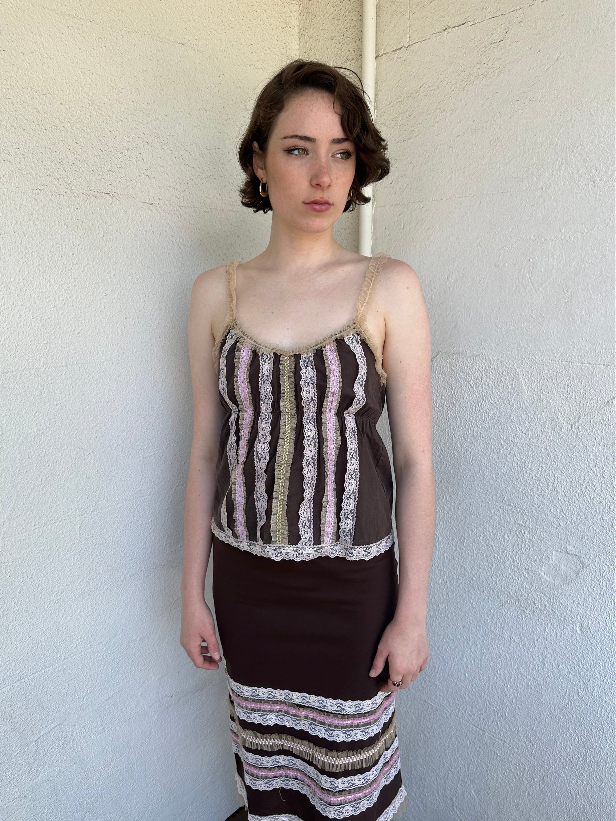 Woman Dressed in Y2K Brown and pink lace trim two piece set featuring a cami top and matching skirt detailed with cream lace and tulle trim throughout.