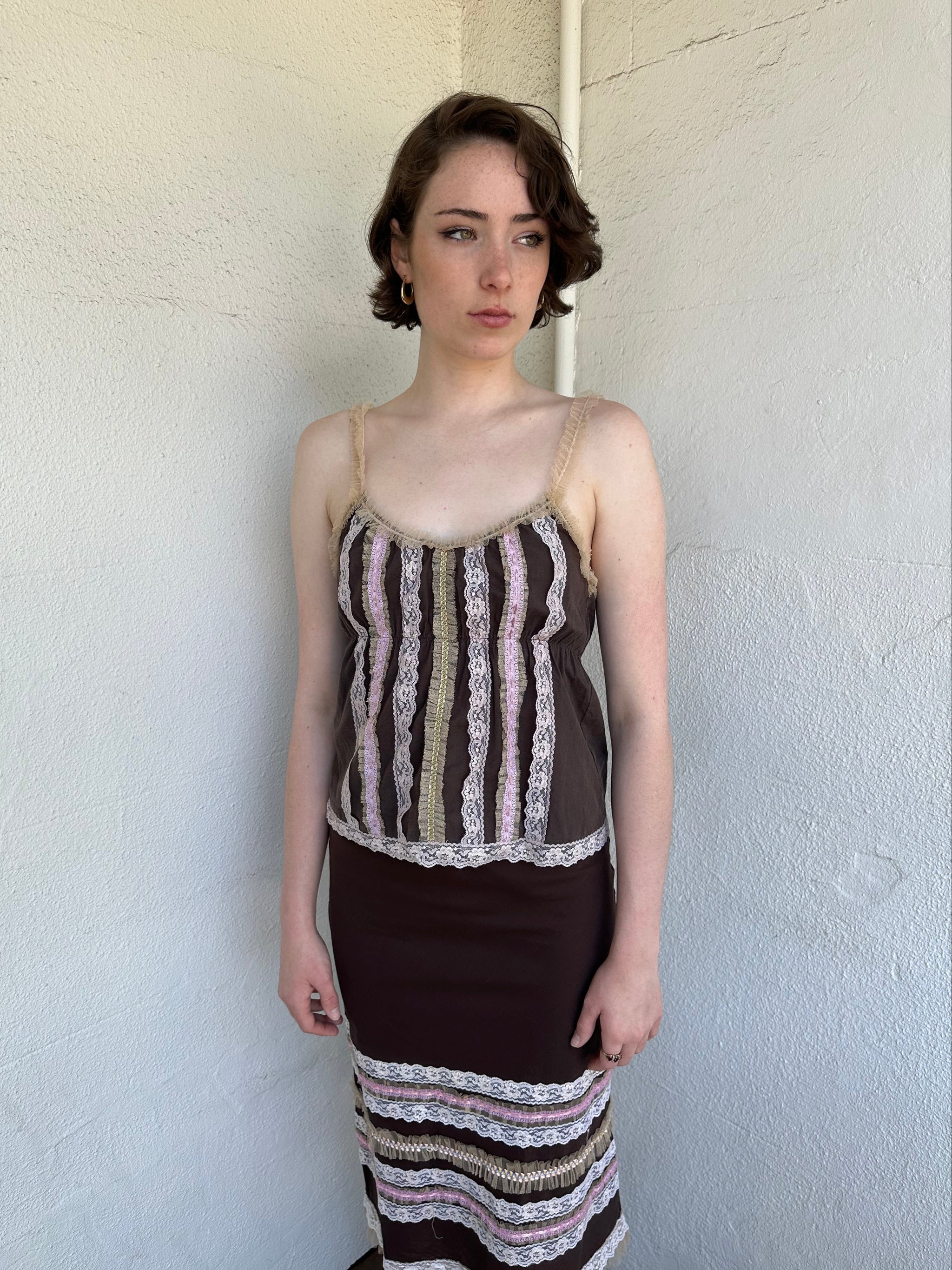 Woman Dressed in Y2K Brown and pink lace trim two piece set featuring a cami top and matching skirt detailed with cream lace and tulle trim throughout.