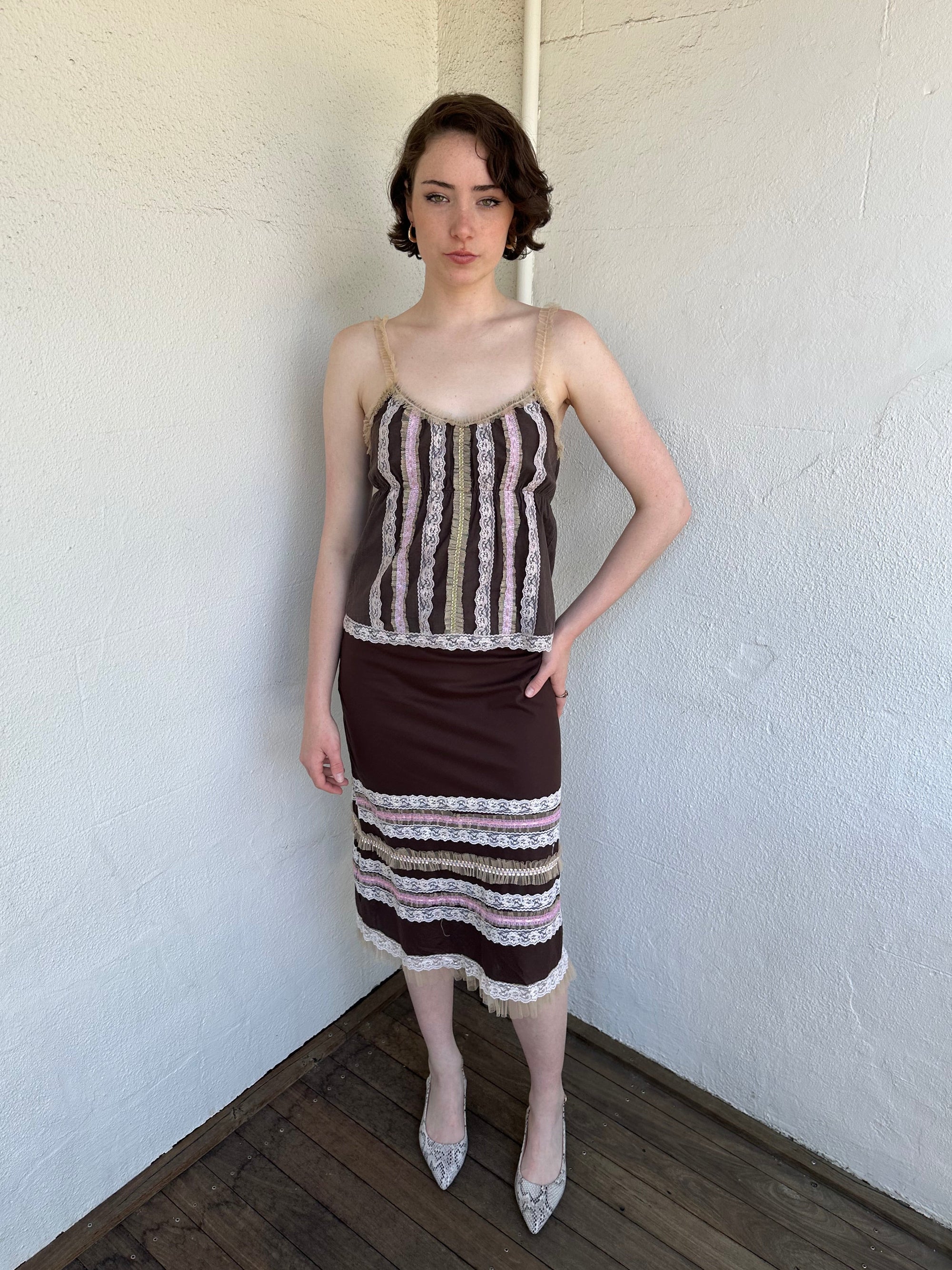 Woman Dressed in Y2K Brown and pink lace trim two piece set featuring a cami top and matching skirt detailed with cream lace and tulle trim throughout.