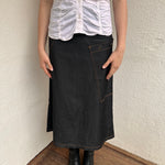 Woman wearing a Y2K 00s Cop Copine black maxi skirt stands out with bold orange contrast stitching and statement grommet details