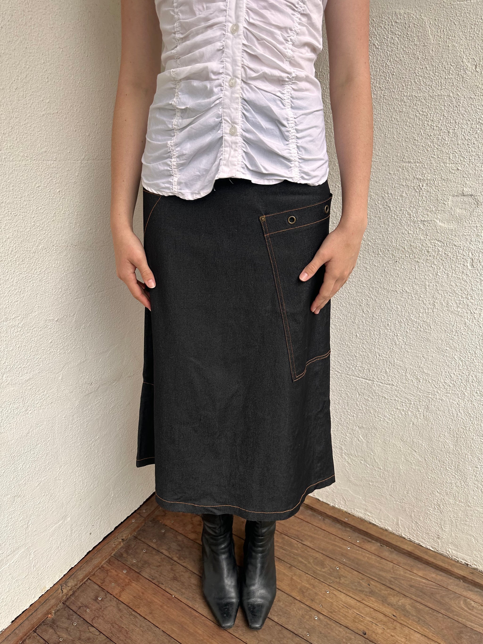 Woman wearing a Y2K 00s Cop Copine black maxi skirt stands out with bold orange contrast stitching and statement grommet details