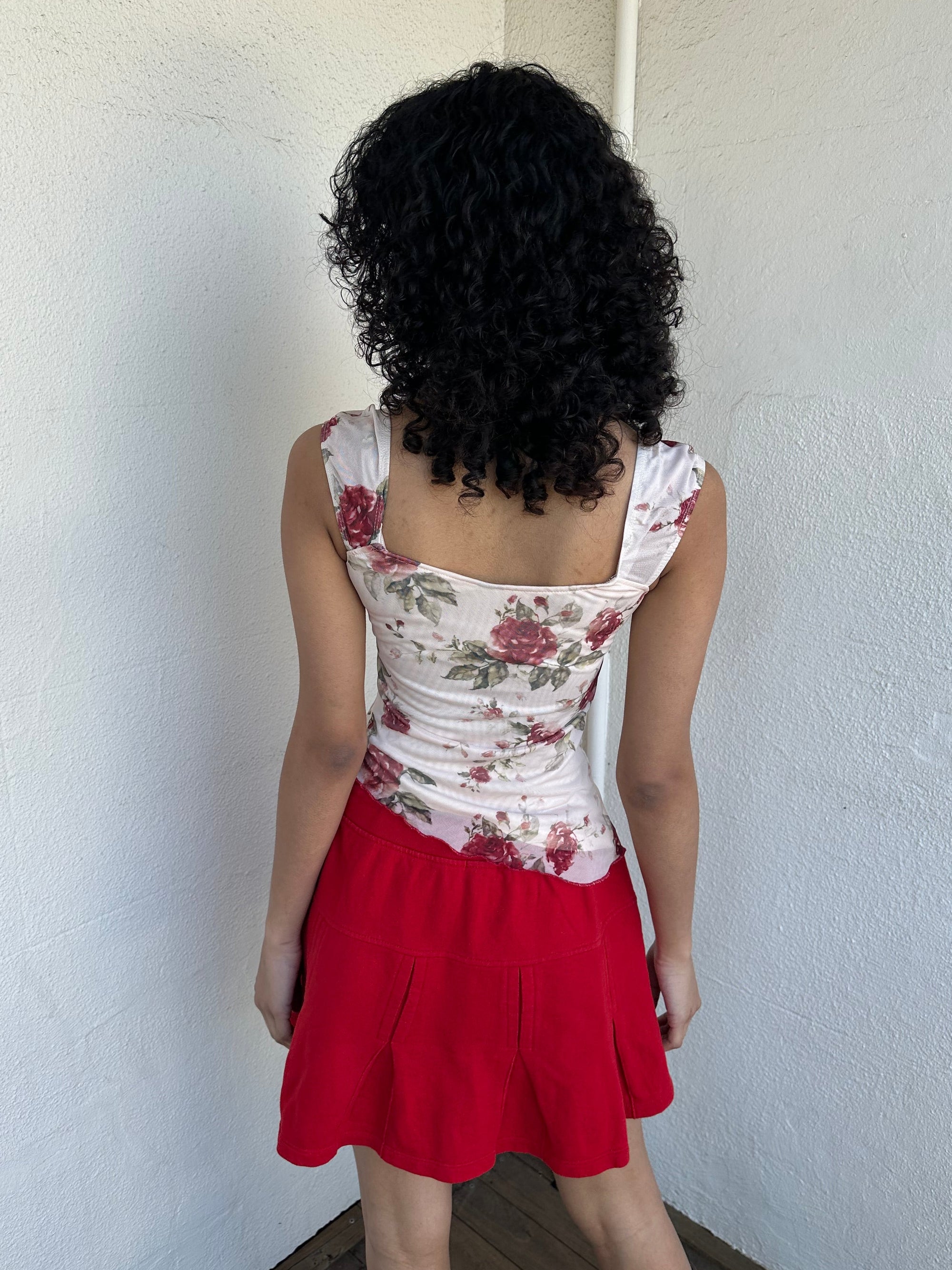 Woman wearing a Y2K 00s cream and red floral mesh tank, with an asymmetric hem and a red underbust ribbon finished with a bow.