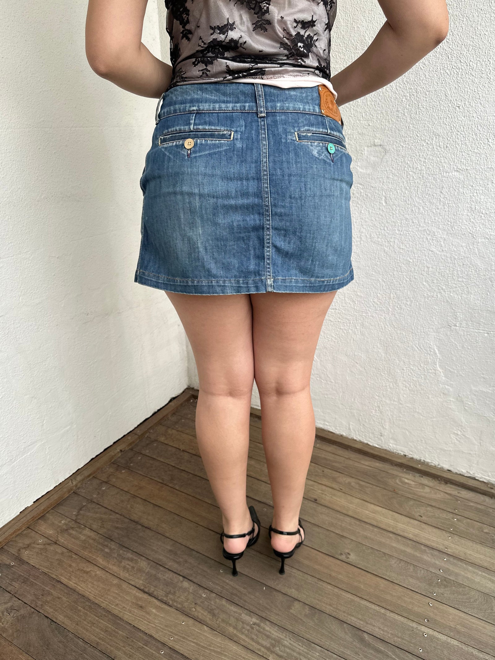 Woman Dressed in Y2K Denim button front wrap mini skirt featuring a classic blue denim finish 