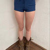 Woman wearing a Y2K 00s Denim look booty shorts feature bold red stitch detailing perfect for.a festival 