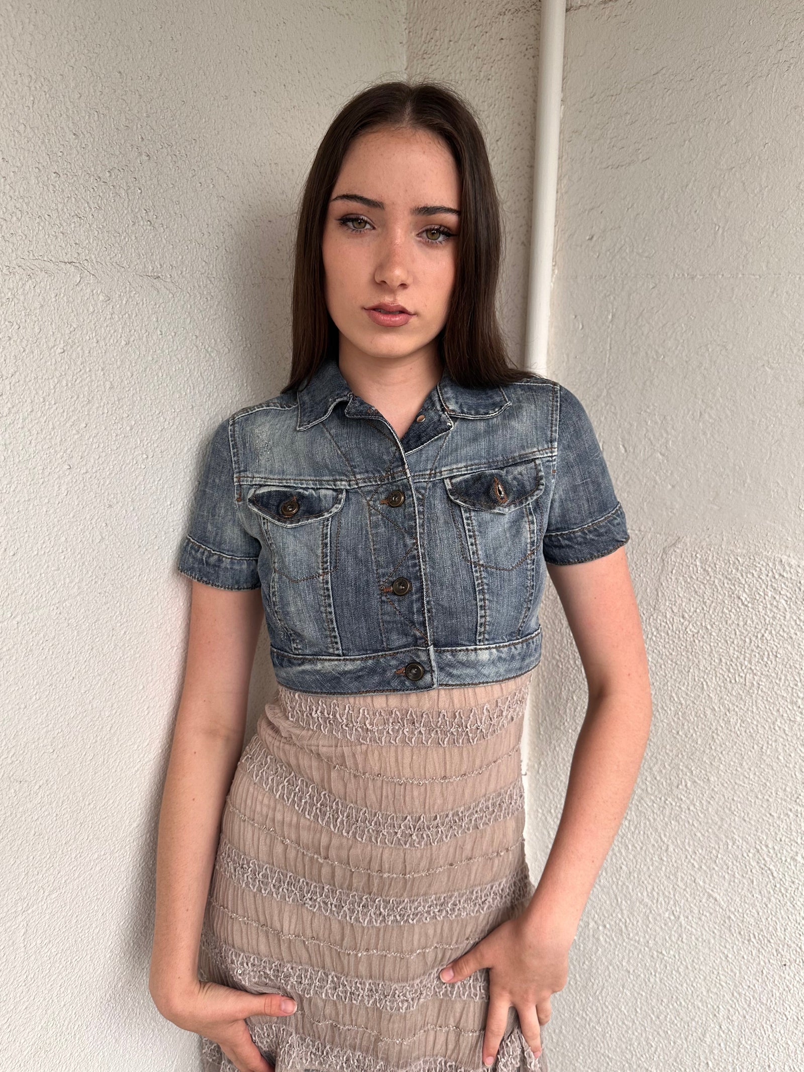 Woman wearing a Y2K 00s Mango washed out denim cropped jacket with a classic button-up front and structured fit