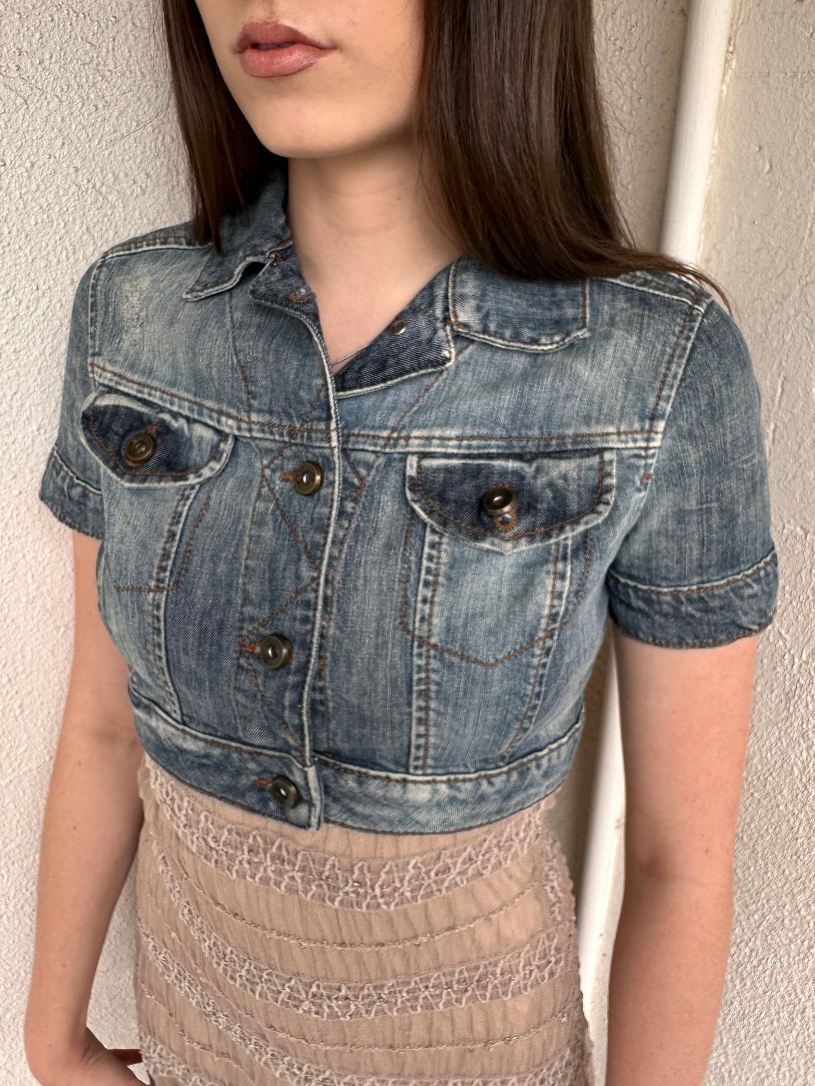 Woman wearing a Y2K 00s Mango washed out denim cropped jacket with a classic button-up front and structured fit