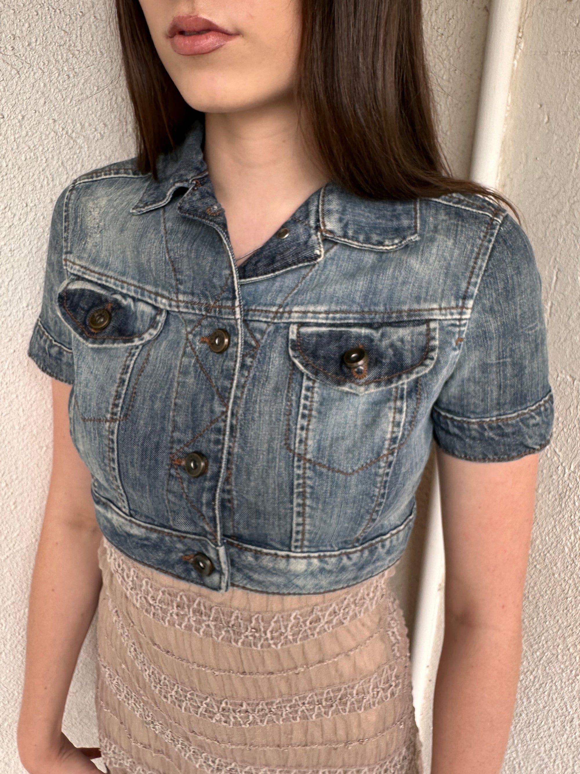Woman wearing a Y2K 00s Mango washed out denim cropped jacket with a classic button-up front and structured fit