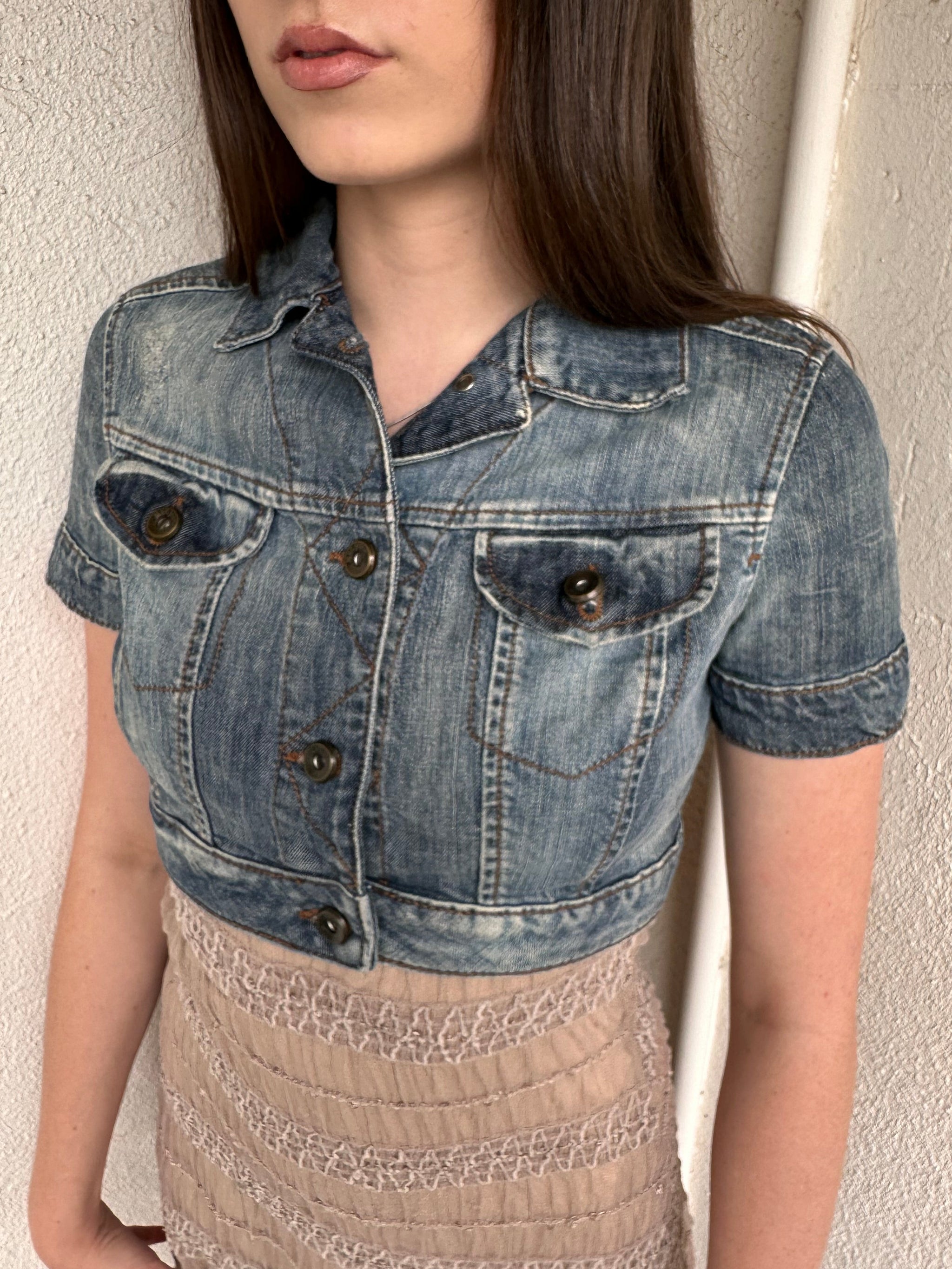 Woman wearing a Y2K 00s Mango washed out denim cropped jacket with a classic button-up front and structured fit