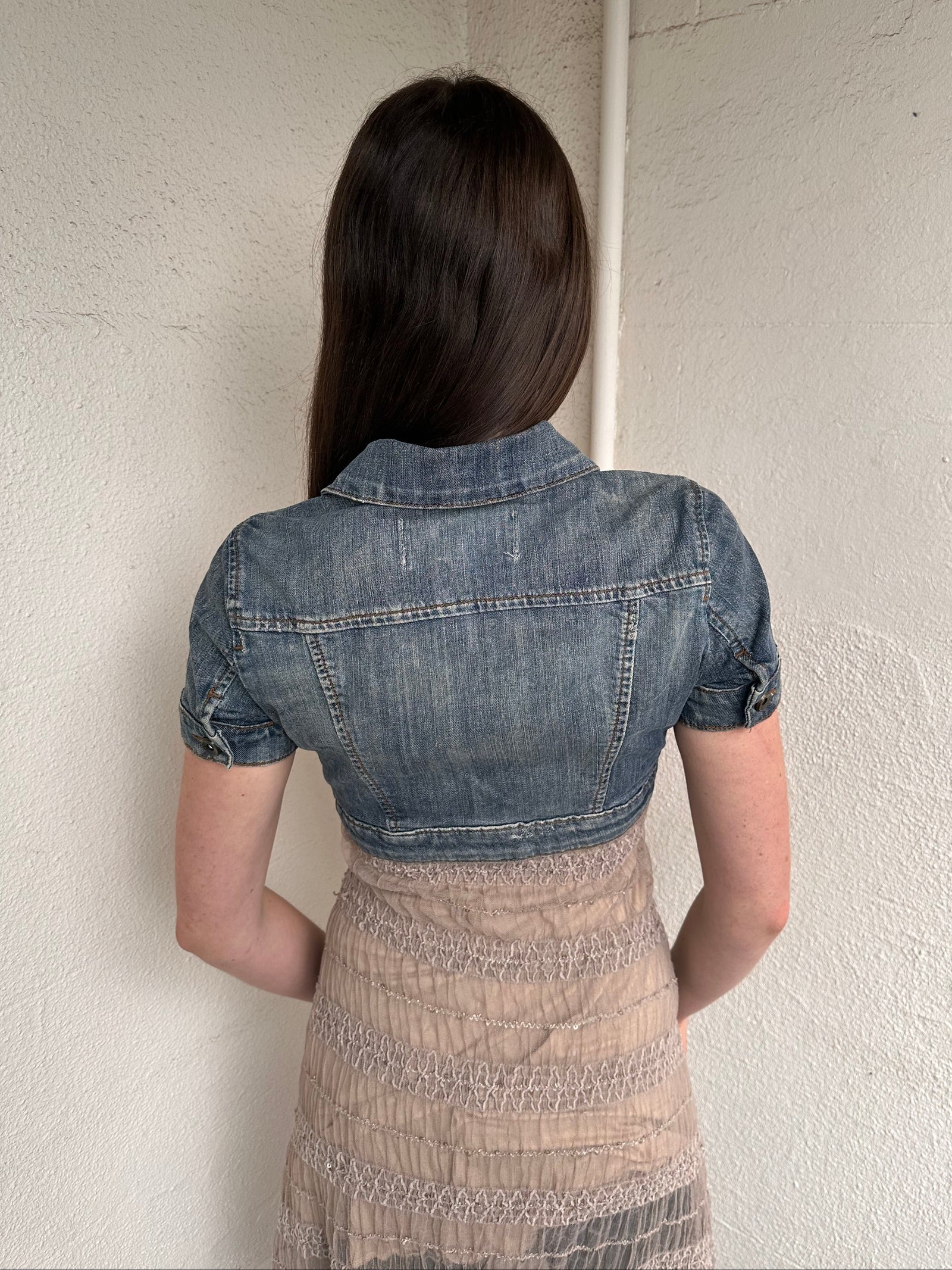 Woman wearing a Y2K 00s Mango washed out denim cropped jacket with a classic button-up front and structured fit