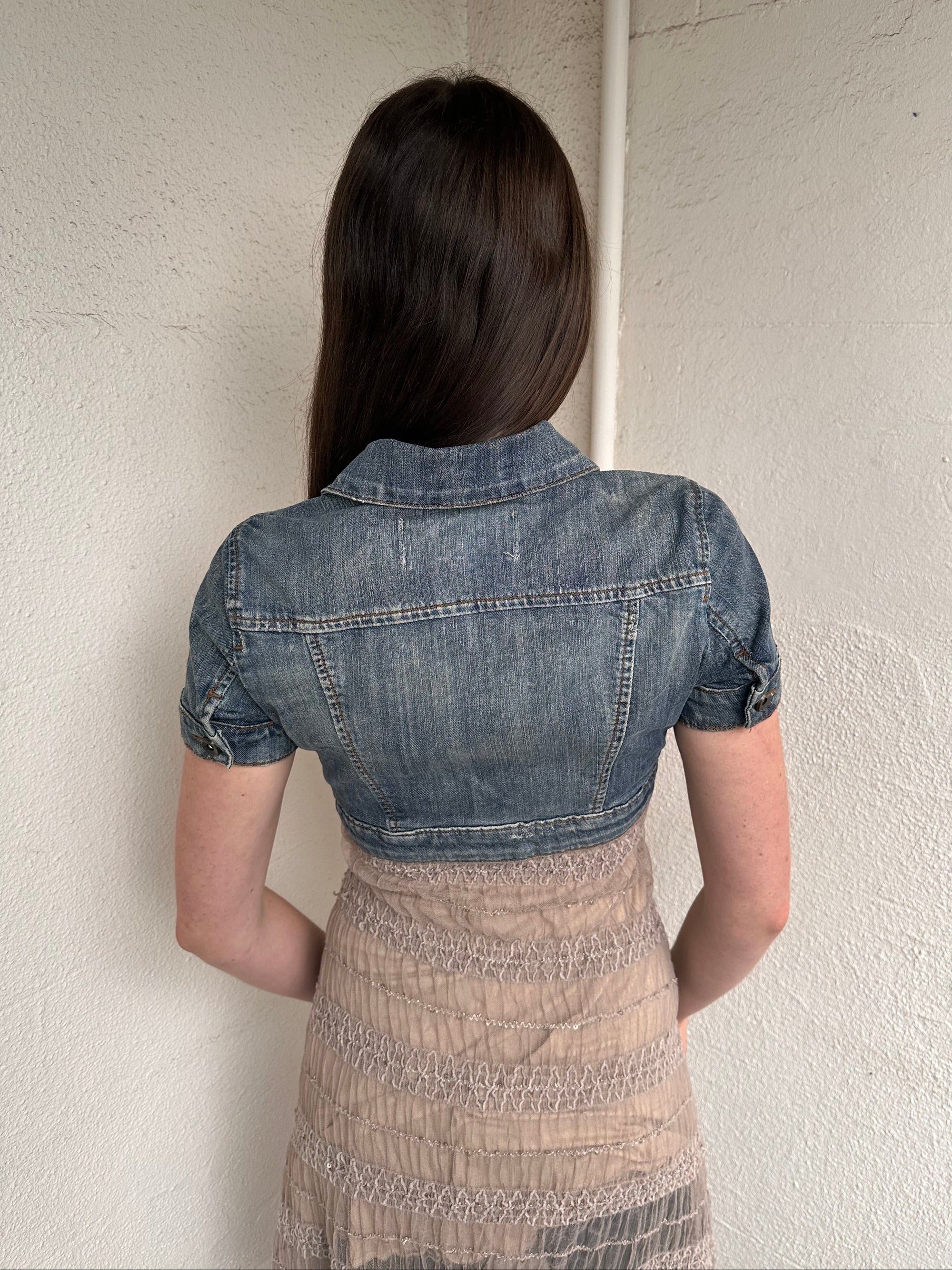 Woman wearing a Y2K 00s Mango washed out denim cropped jacket with a classic button-up front and structured fit