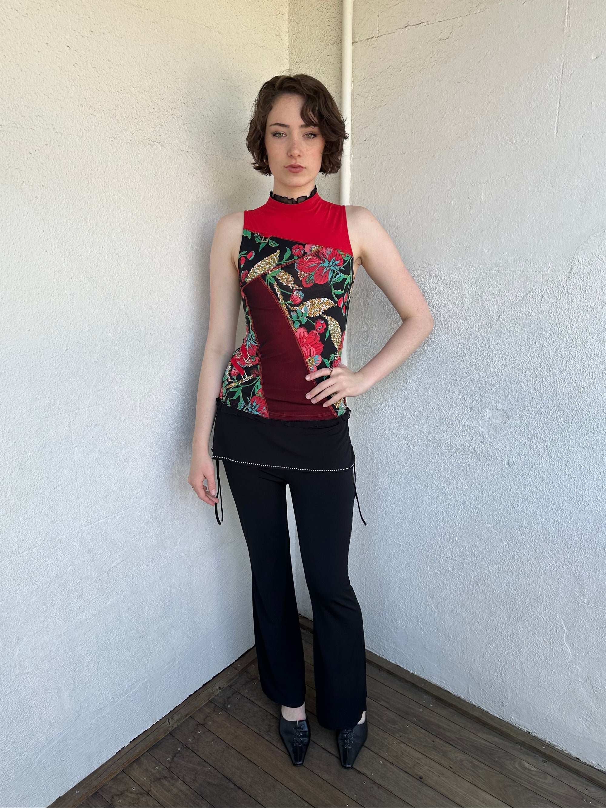 Woman Dressed in Y2K Red and black patchwork floral top featuring a mixed floral patchwork design in red and black tones with silver square ring detailing throughout.
