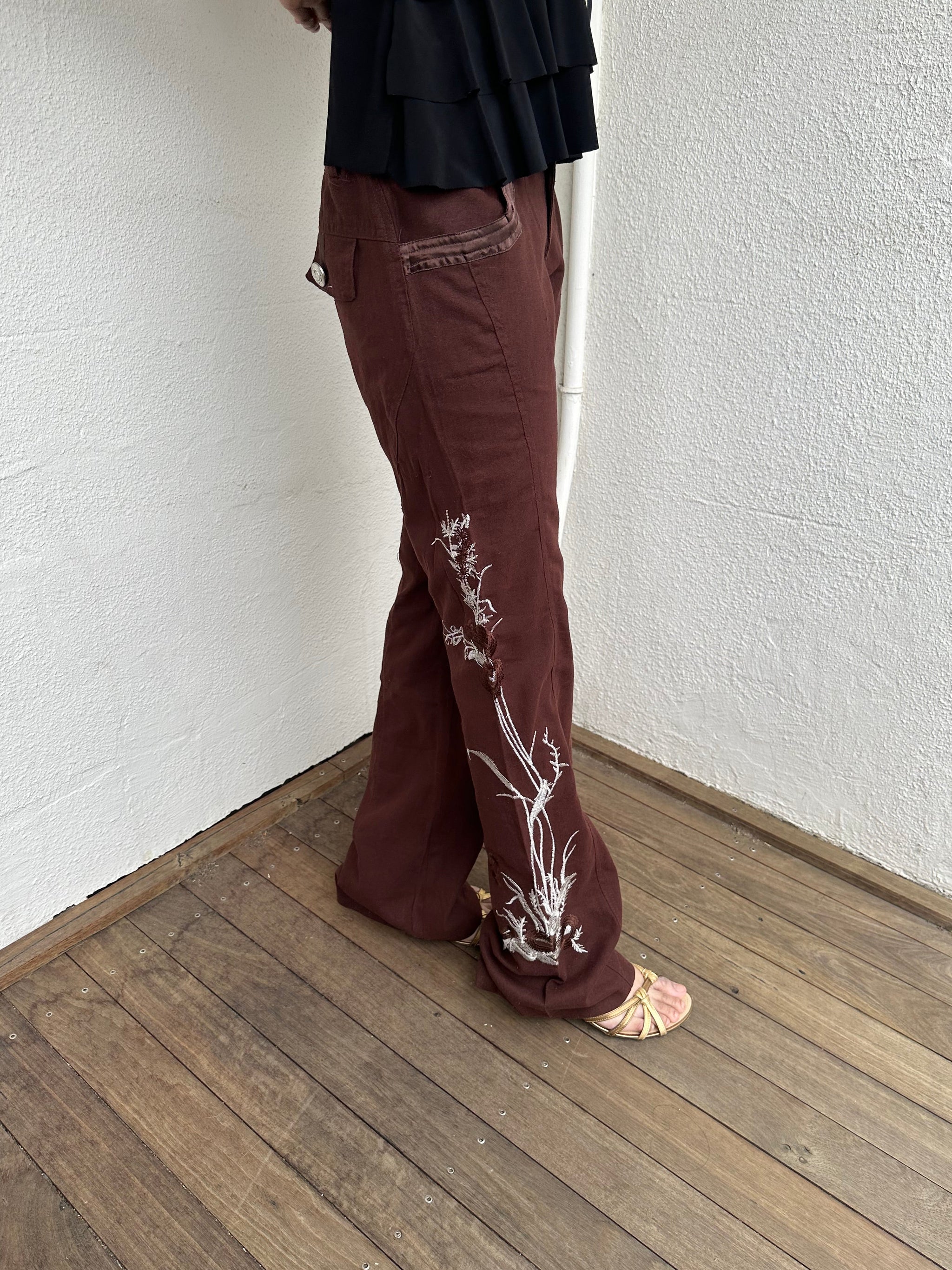 Woman Dressed in Y2K 00s Embroidery detail brown Y2K cargo pants featuring a rich brown tone with white floral leaf embroidery