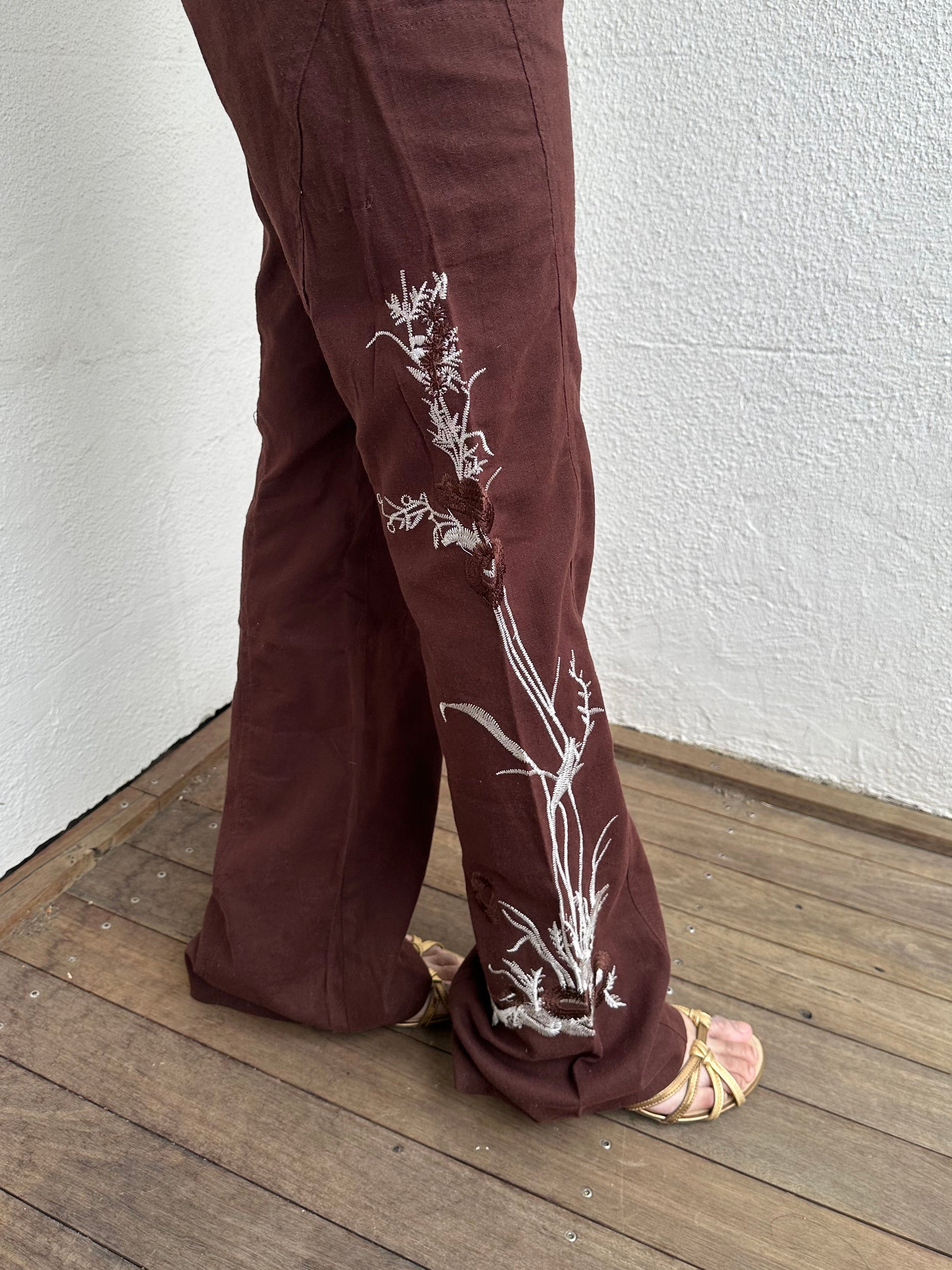 Woman Dressed in Y2K 00s Embroidery detail brown Y2K cargo pants featuring a rich brown tone with white floral leaf embroidery
