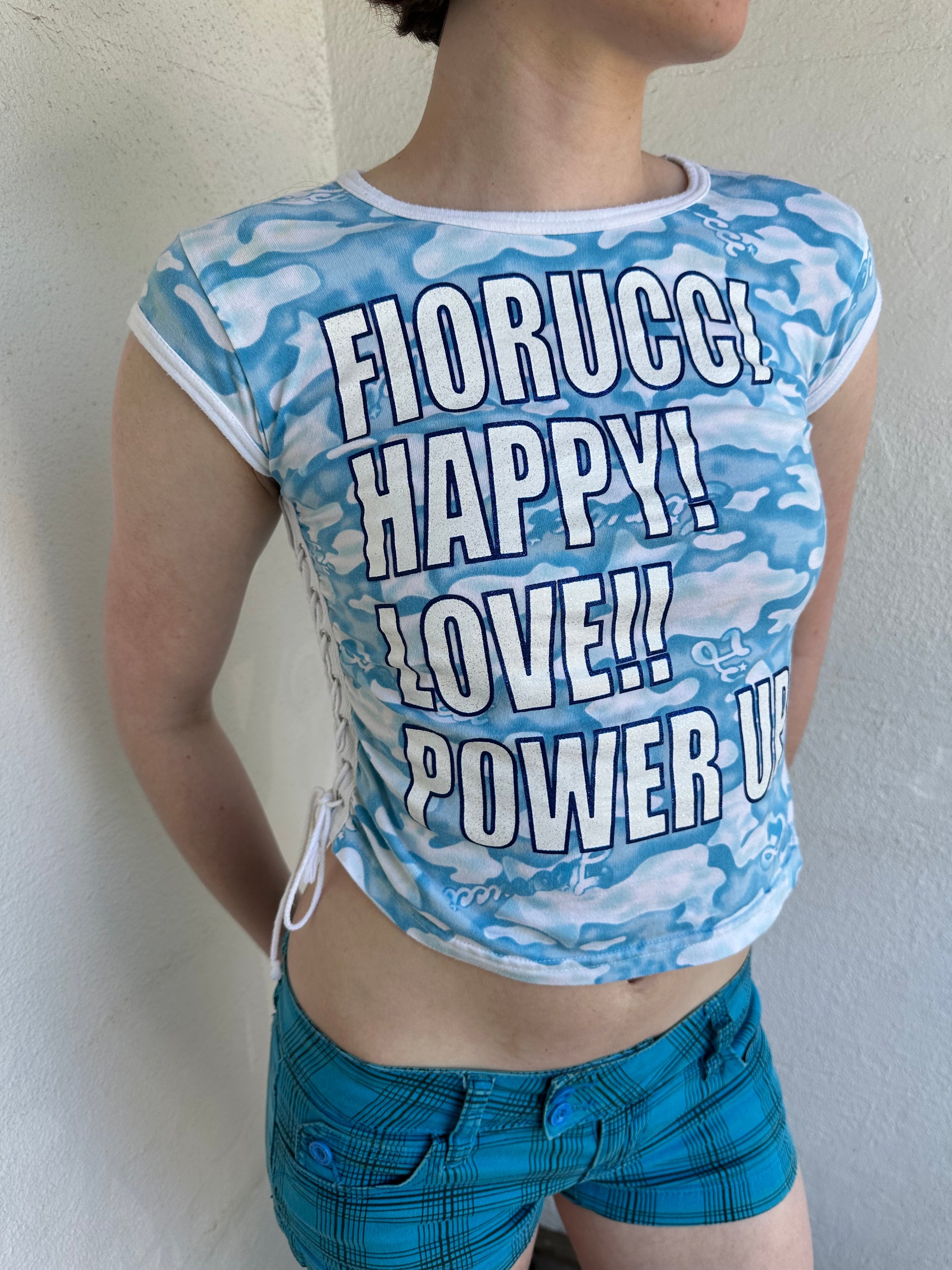 Woman Dressed in Y2K 2000s Fiorucci blue cloud graphic t-shirt featuring a cloud graphic background with large spell-out text 