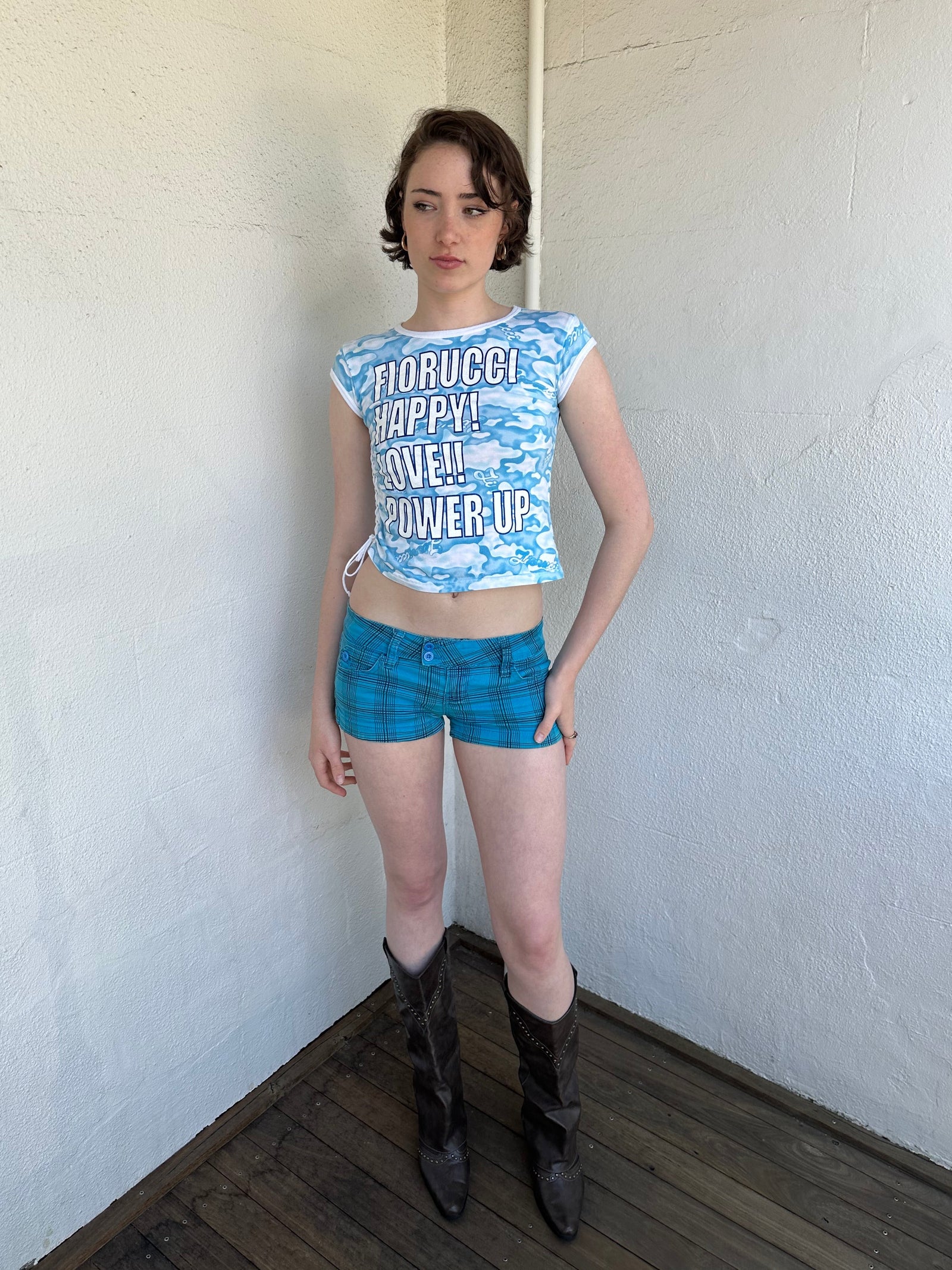 Woman Dressed in Y2K 2000s Fiorucci blue cloud graphic t-shirt featuring a cloud graphic background with large spell-out text 