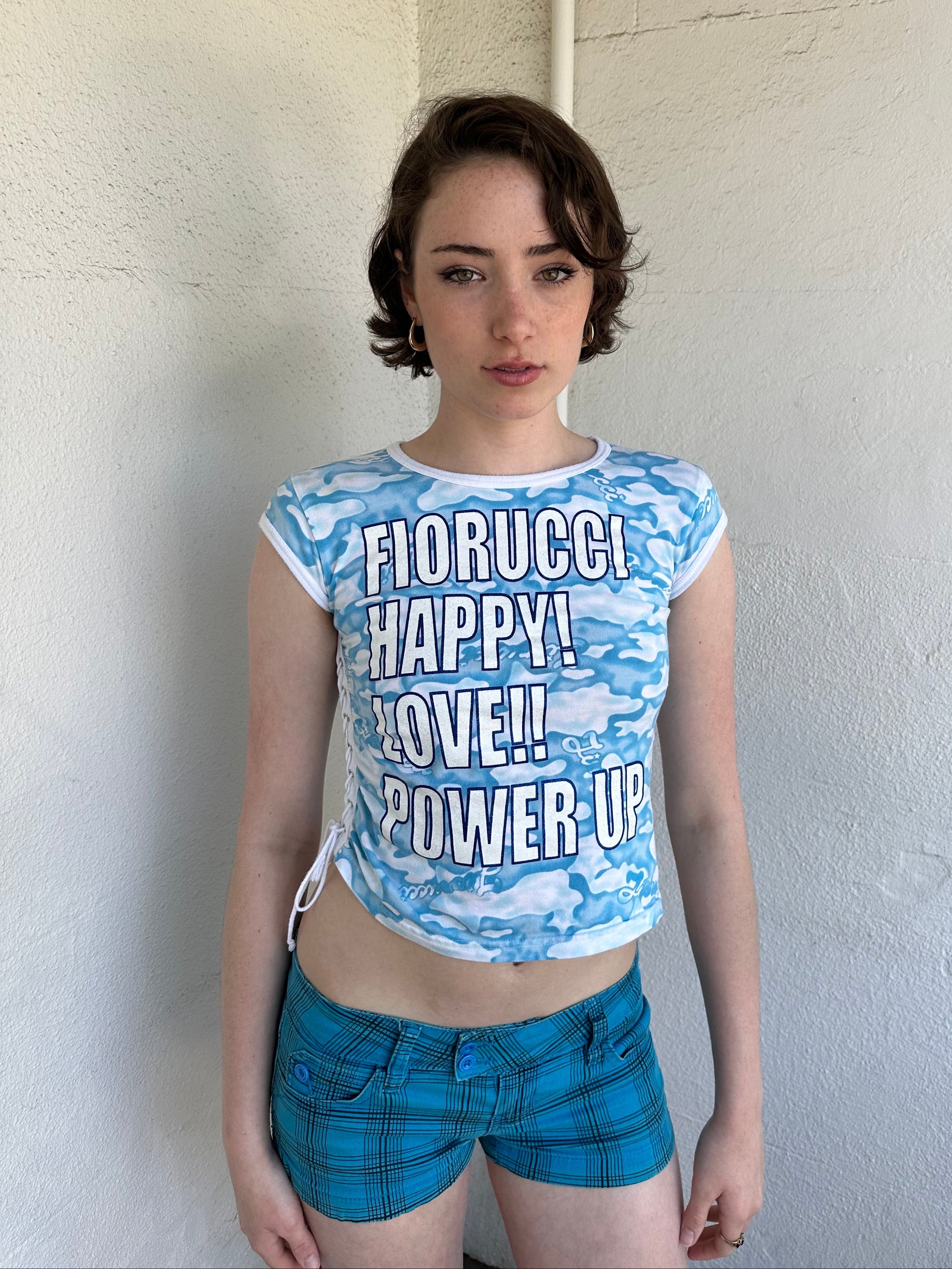 Woman Dressed in Y2K 2000s Fiorucci blue cloud graphic t-shirt featuring a cloud graphic background with large spell-out text 