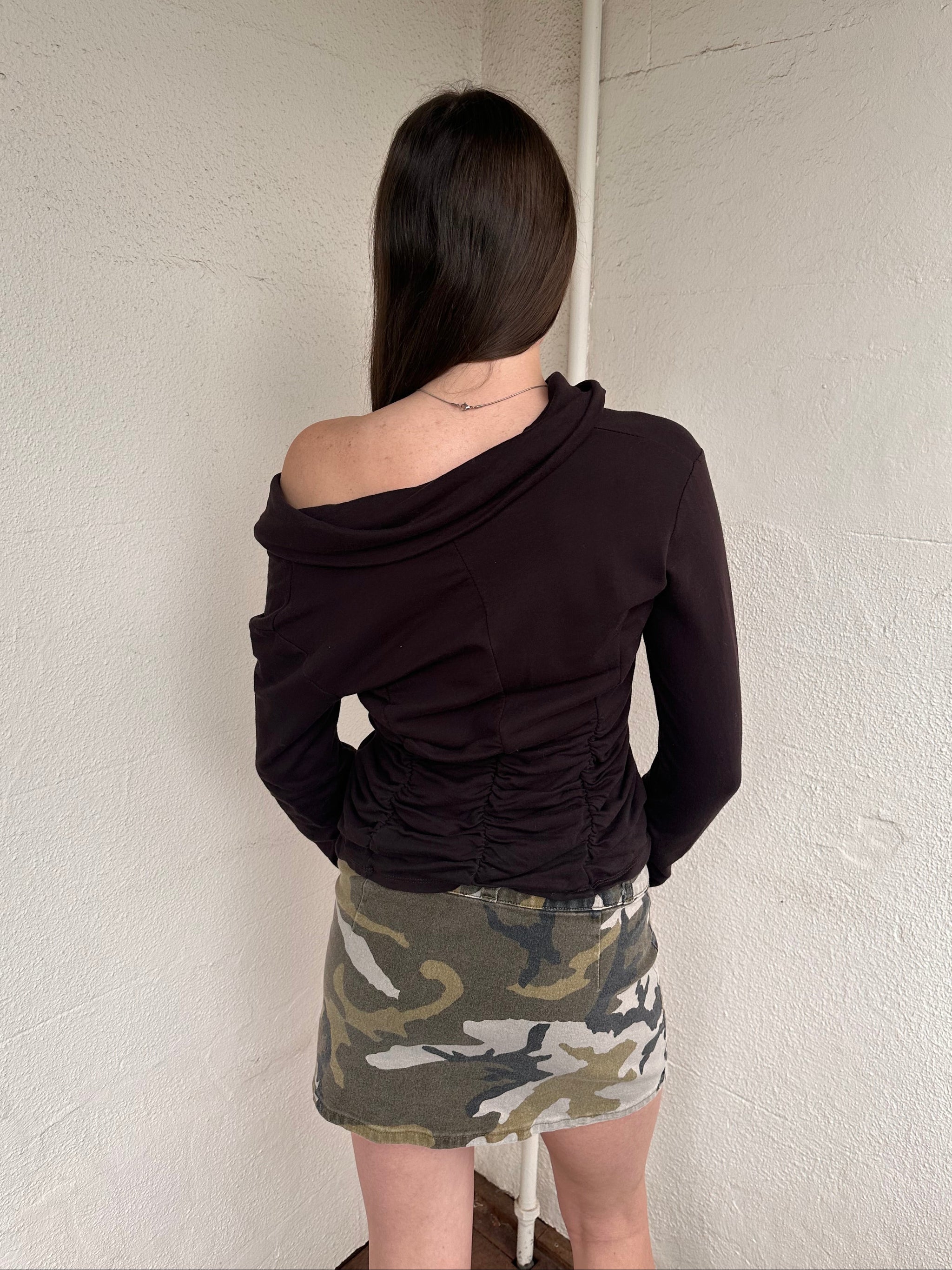 Women wearing a 00s Y2K Green camo denim mini skirt with a built-in belt. Crafted from sturdy denim with cargo-style detailing for added texture