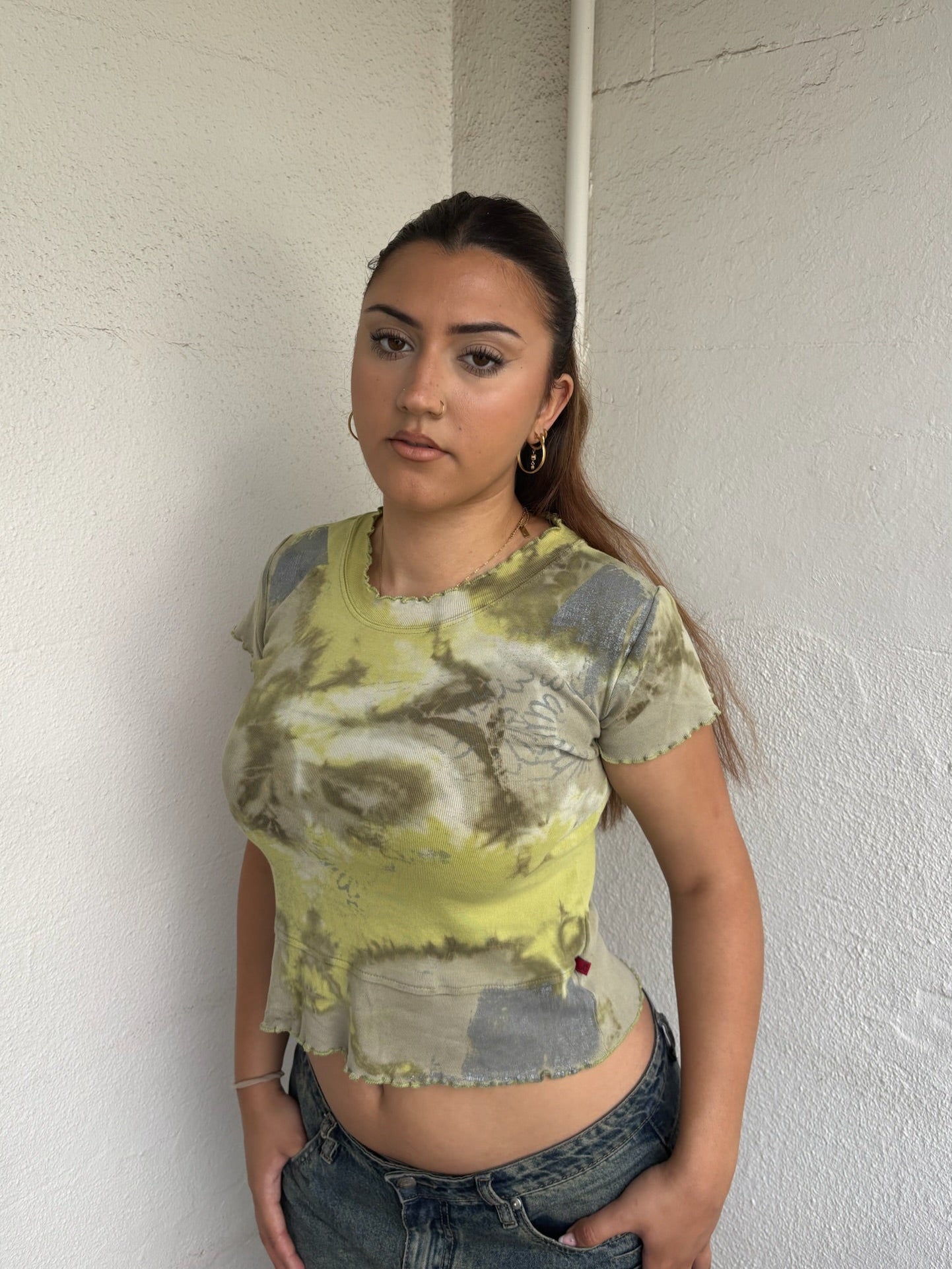 Woman Dressed in Y2K 00s Green and grey tie dye baby t-shirt featuring a stunning marble-style pattern throughout. 