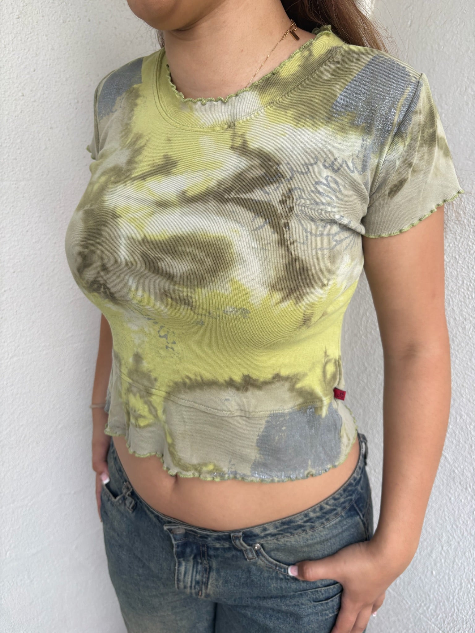 Woman Dressed in Y2K 00s Green and grey tie dye baby t-shirt featuring a stunning marble-style pattern throughout. 