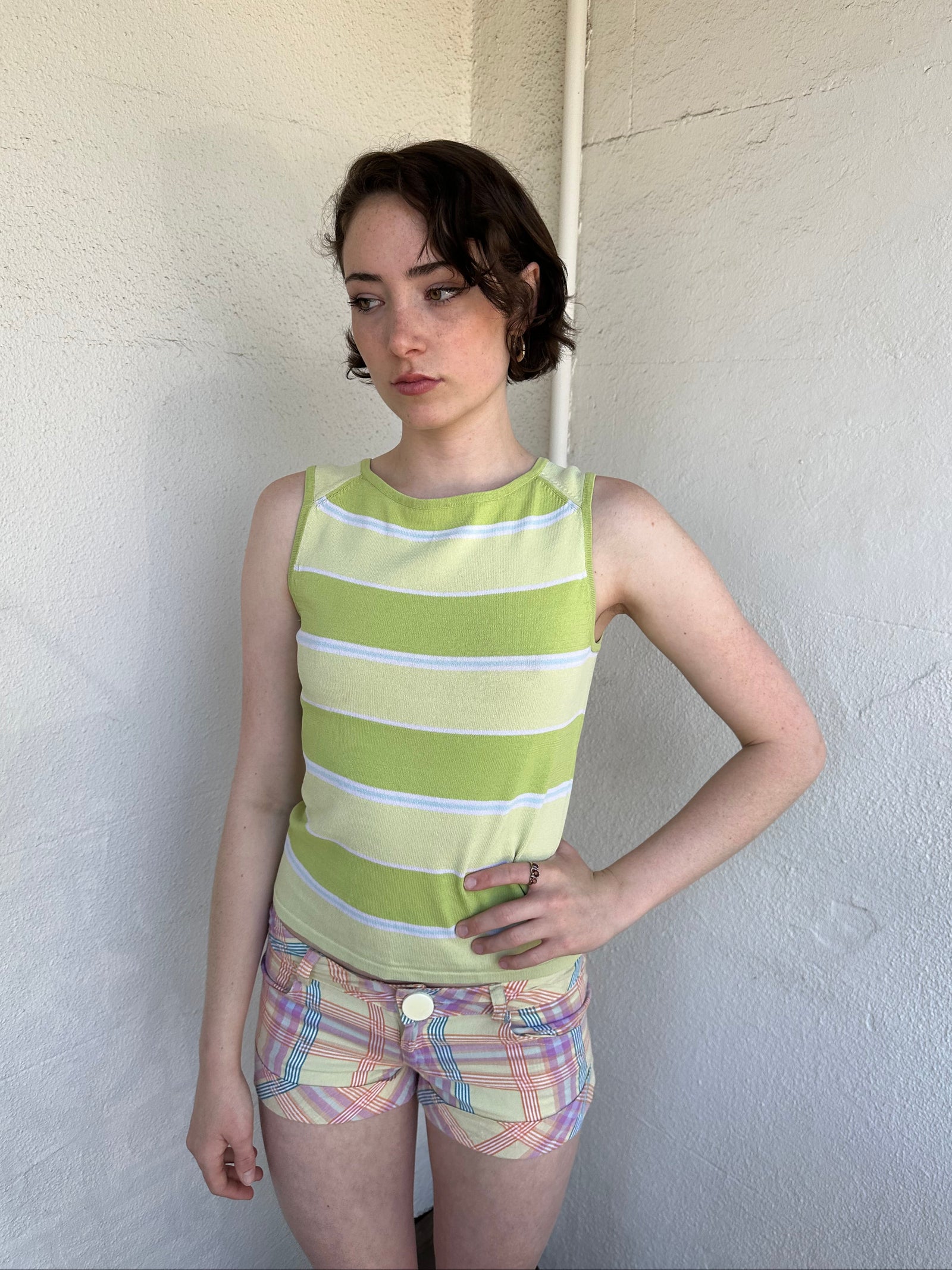 Woman Dressed in Y2K Green stripe knitted tank top featuring alternating horizontal stripes in pastel green and lime green 