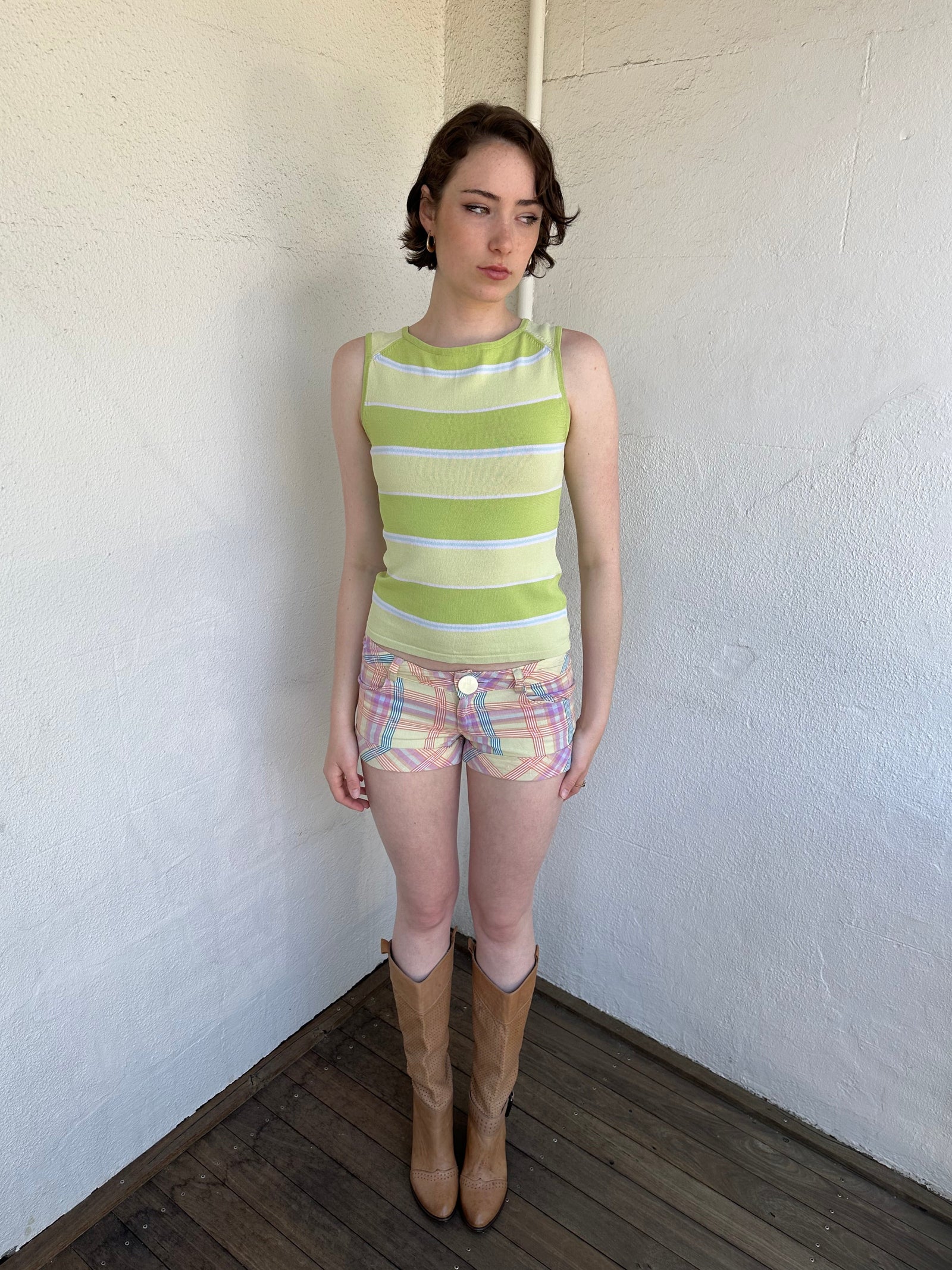 Woman Dressed in Y2K Green stripe knitted tank top featuring alternating horizontal stripes in pastel green and lime green 