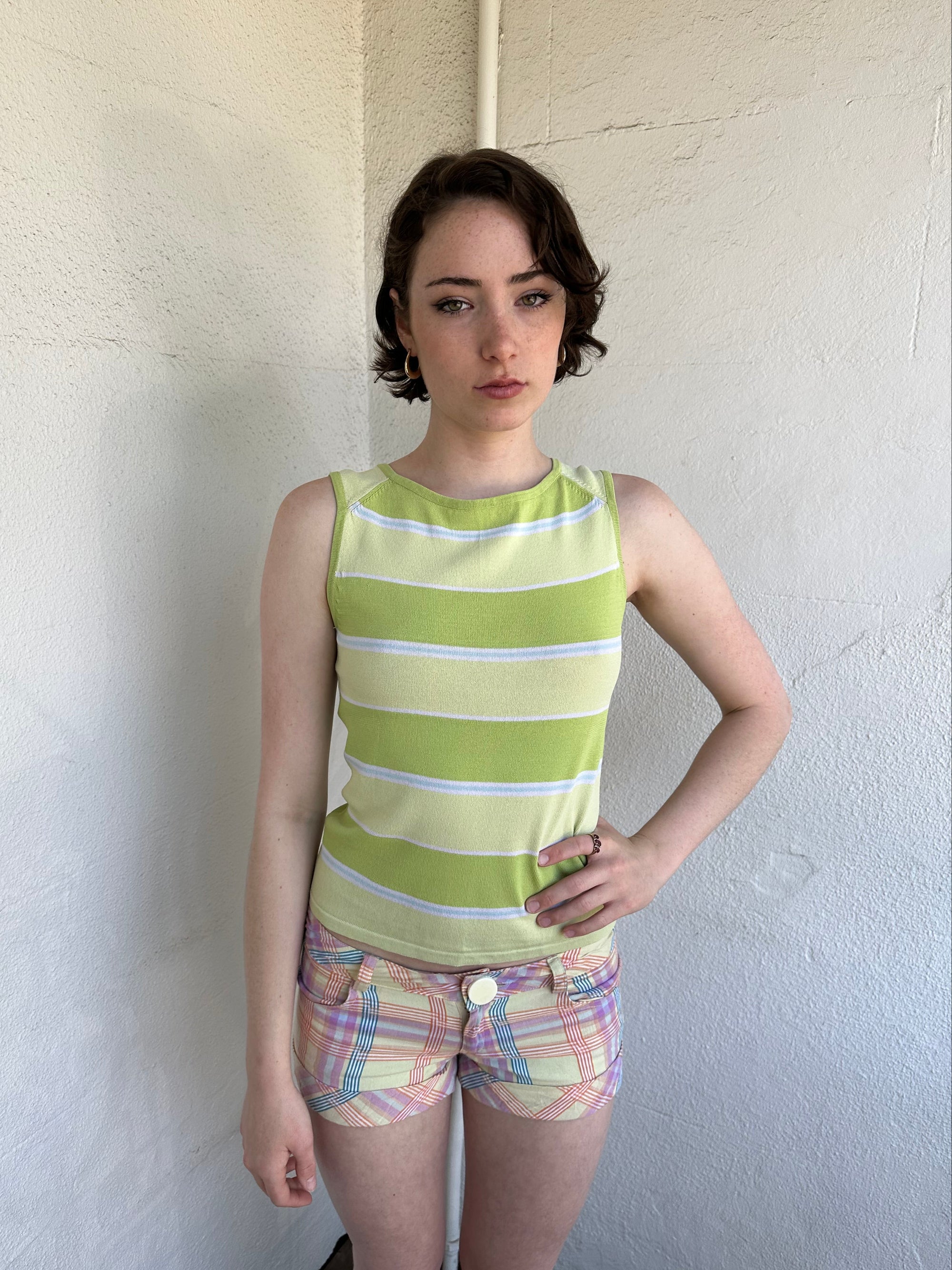 Woman Dressed in Y2K Green stripe knitted tank top featuring alternating horizontal stripes in pastel green and lime green 