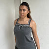 Woman Dressed in Y2K 00s Grey lace trimmed cami featuring a soft grey jersey material with lace trim along the neckline. 