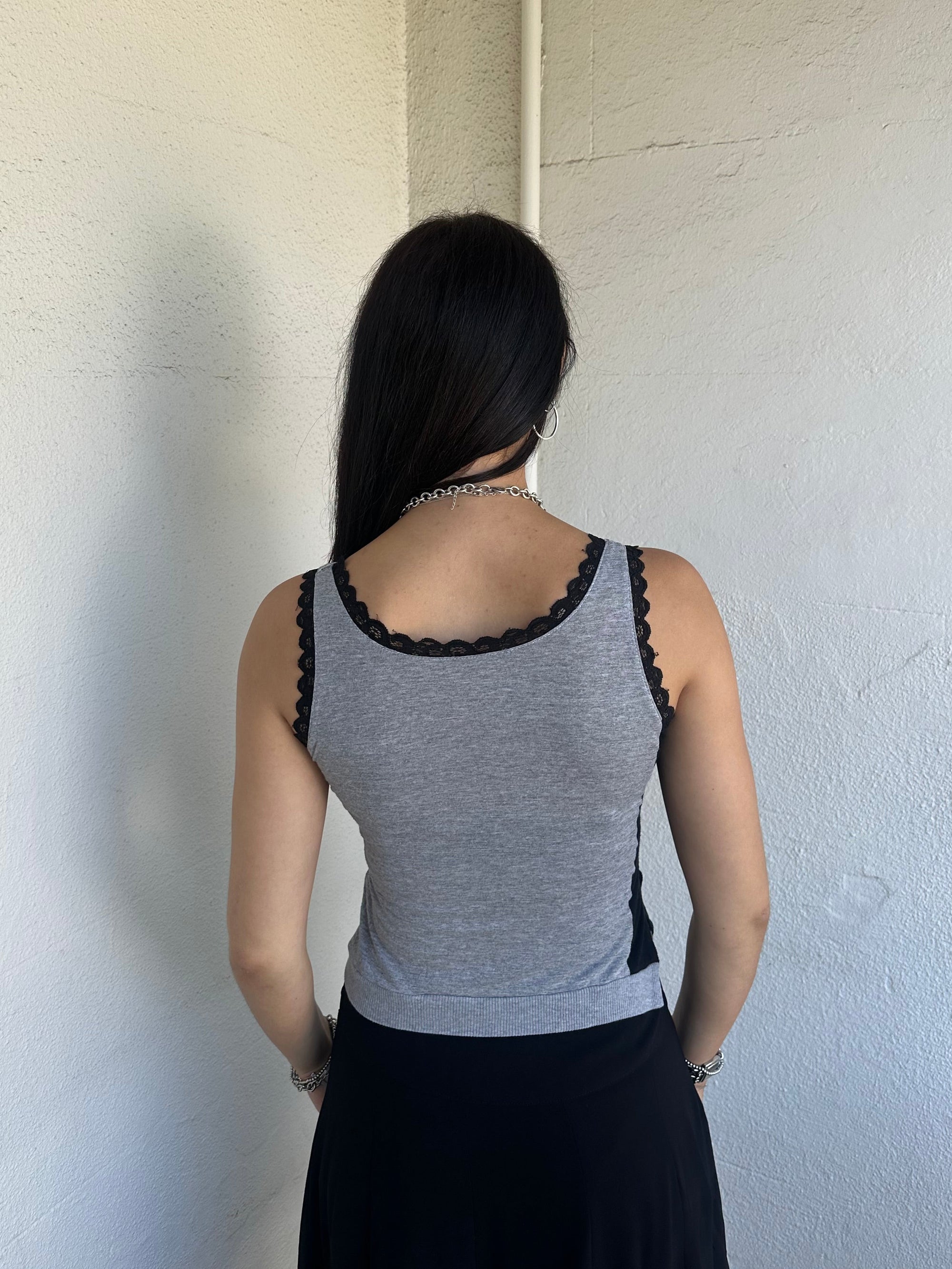 Woman Dressed in Y2K 00s Grey graphic tank top featuring a grey base with white and black graphic print on the front.