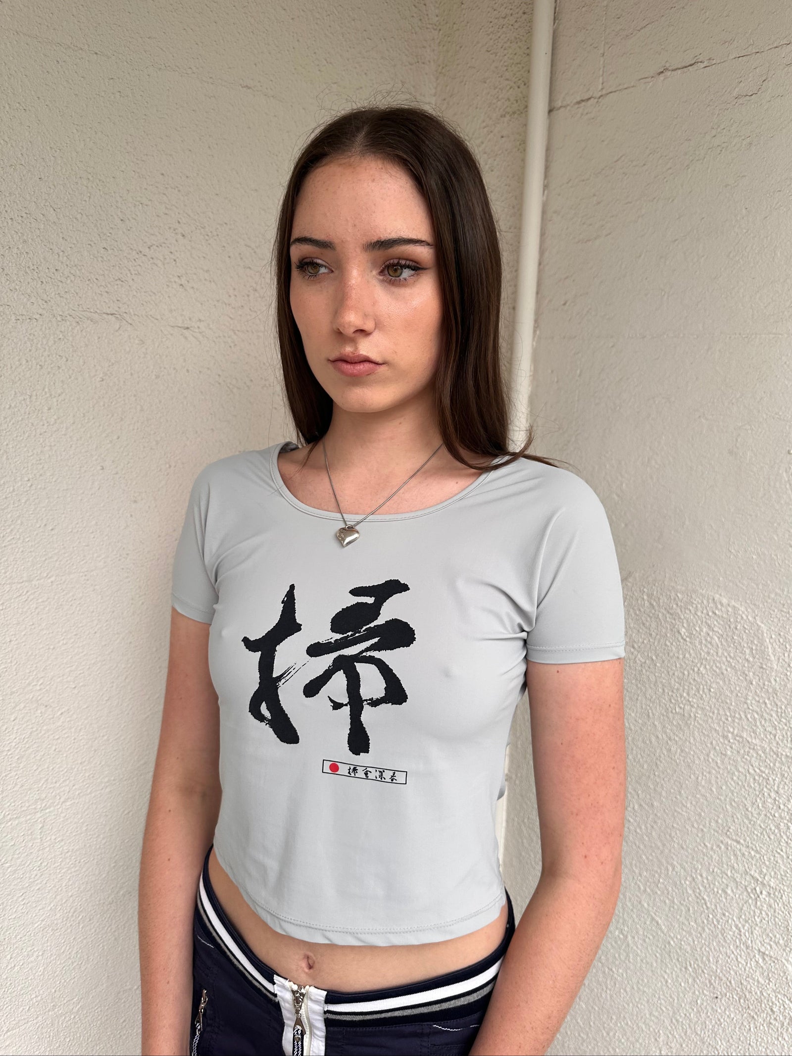 Woman wearing a Y2K 00s Grey baby t-shirt featuring an all-over Japanese symbol print