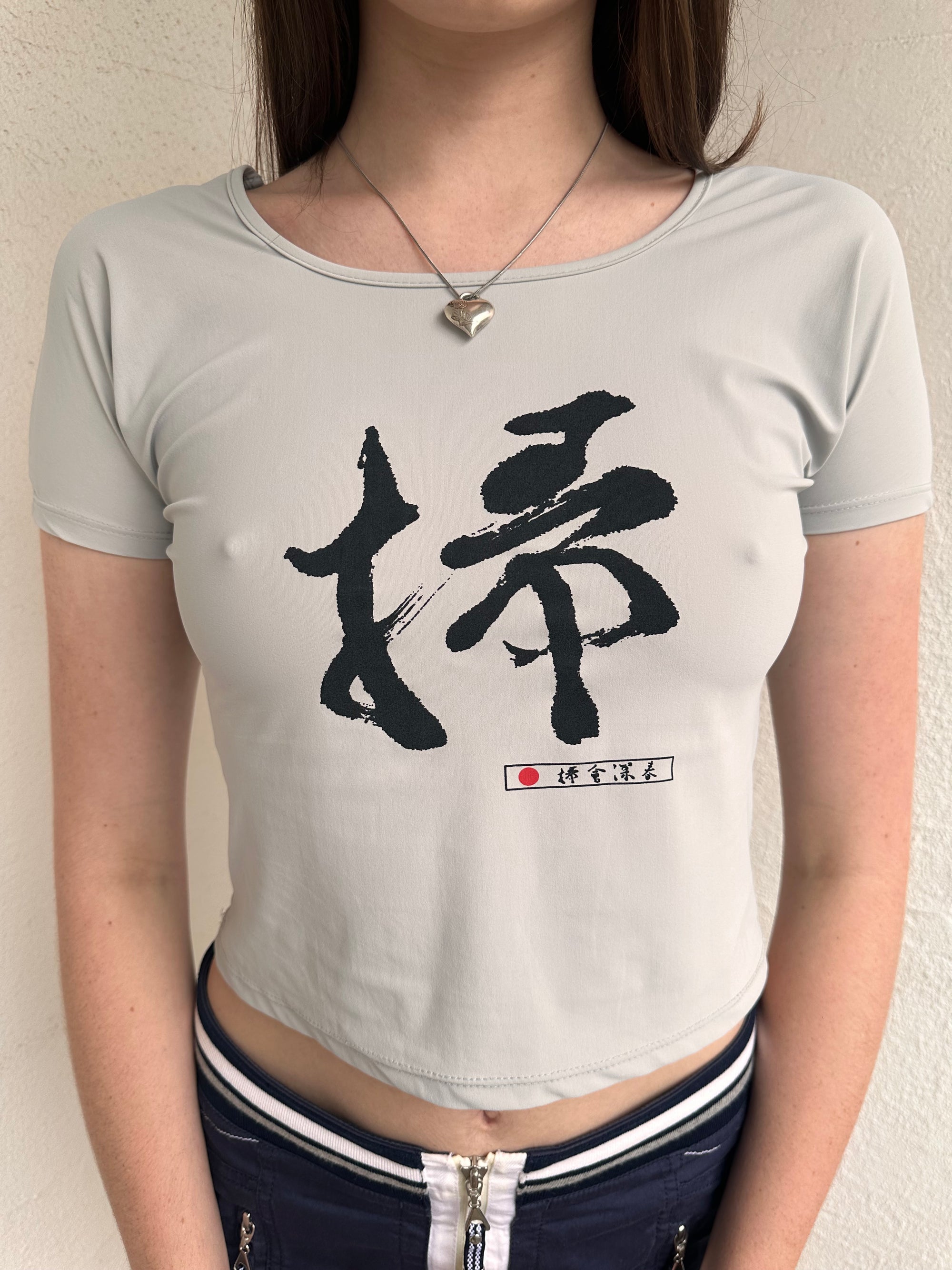 Woman wearing a Y2K 00s Grey baby t-shirt featuring an all-over Japanese symbol print