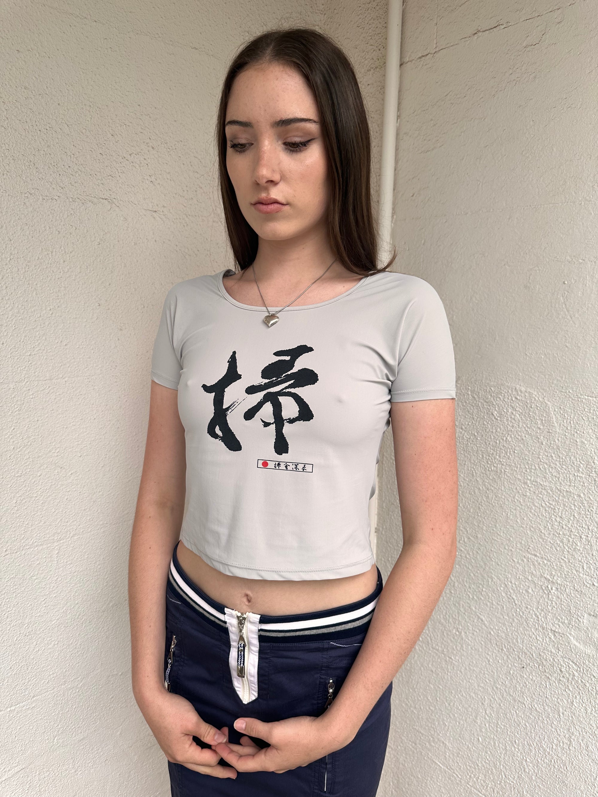 Woman wearing a Y2K 00s Grey baby t-shirt featuring an all-over Japanese symbol print